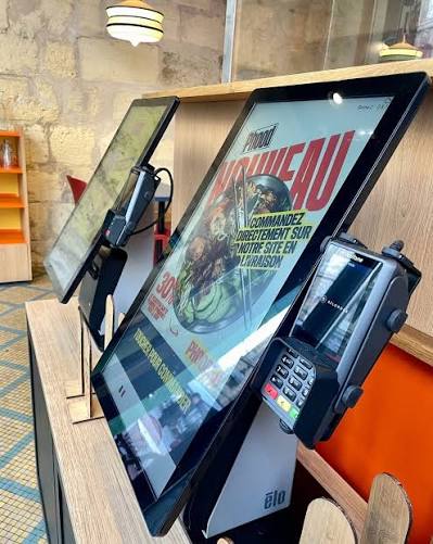Borne de commande et terminal de paiement posés sur le comptoir d'un restaurant