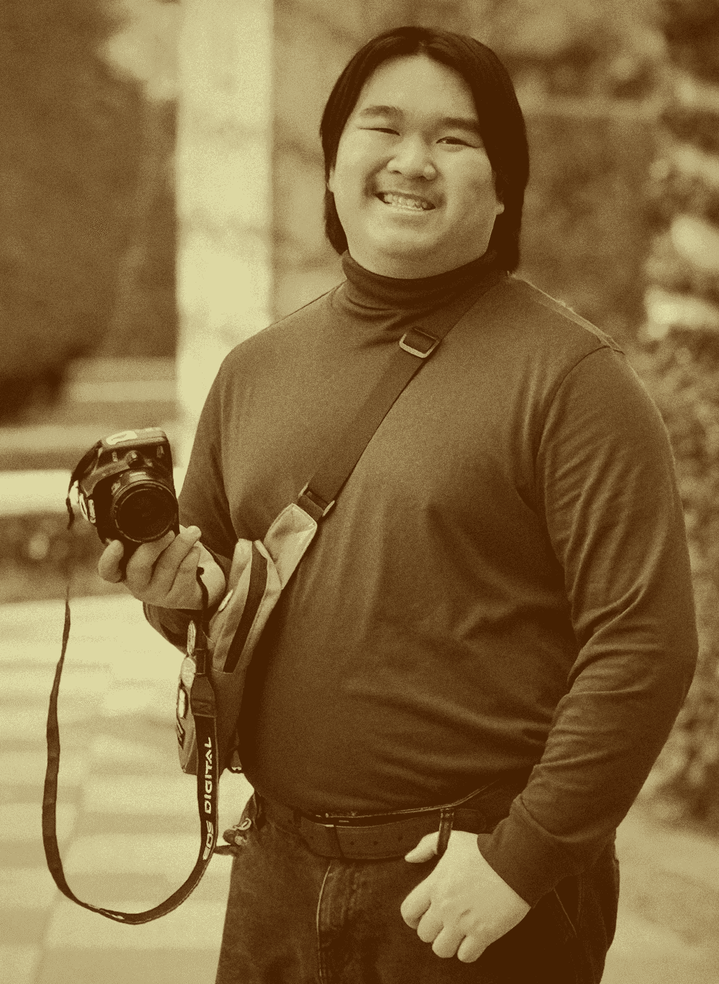 Photo of Evan Saisenesouk holding a Canon XSI Rebel camera in an outdoor garden in Madrid