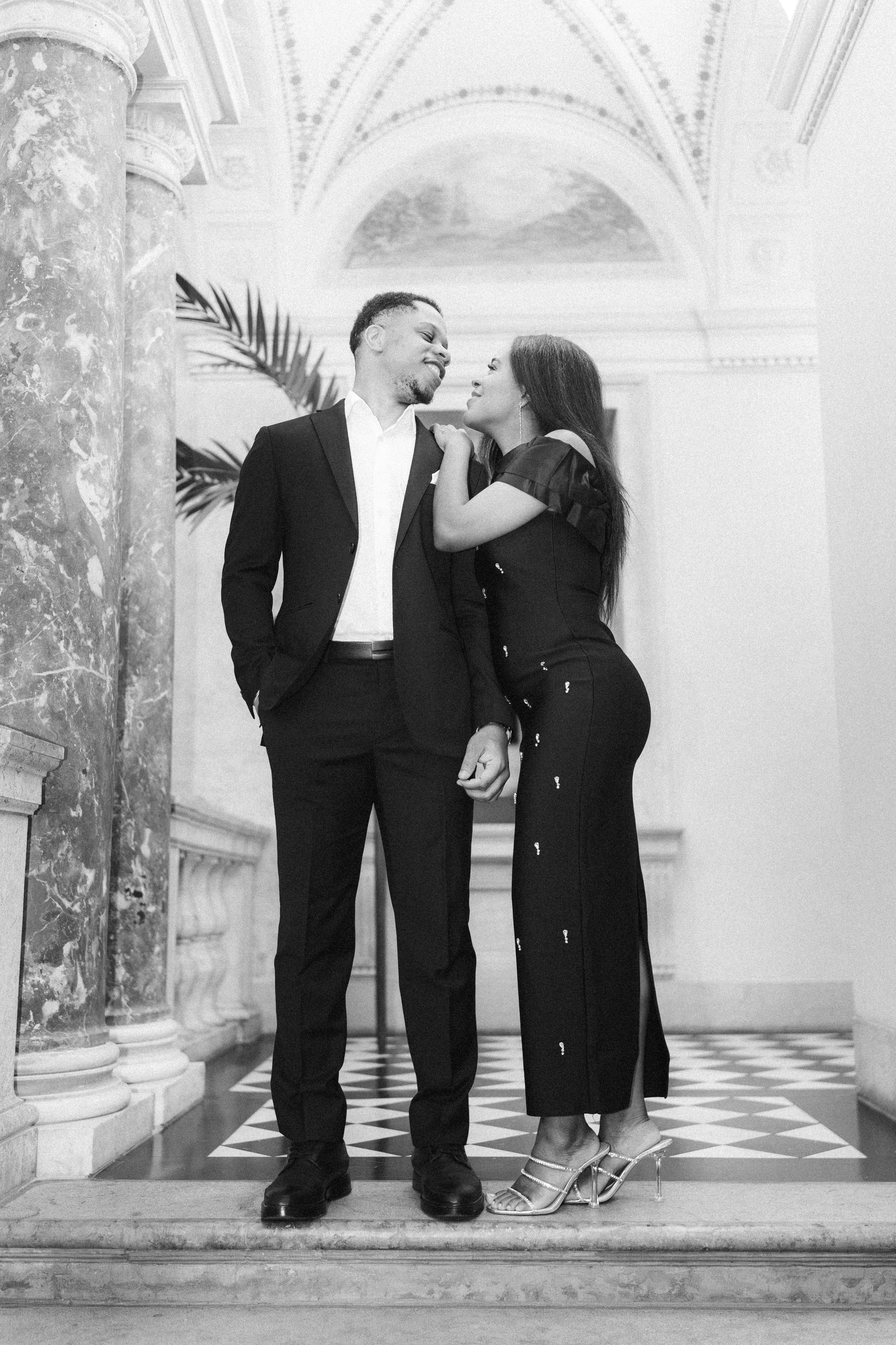 A serene outdoor wedding setup with white chairs arranged on green grass under a canopy of trees.