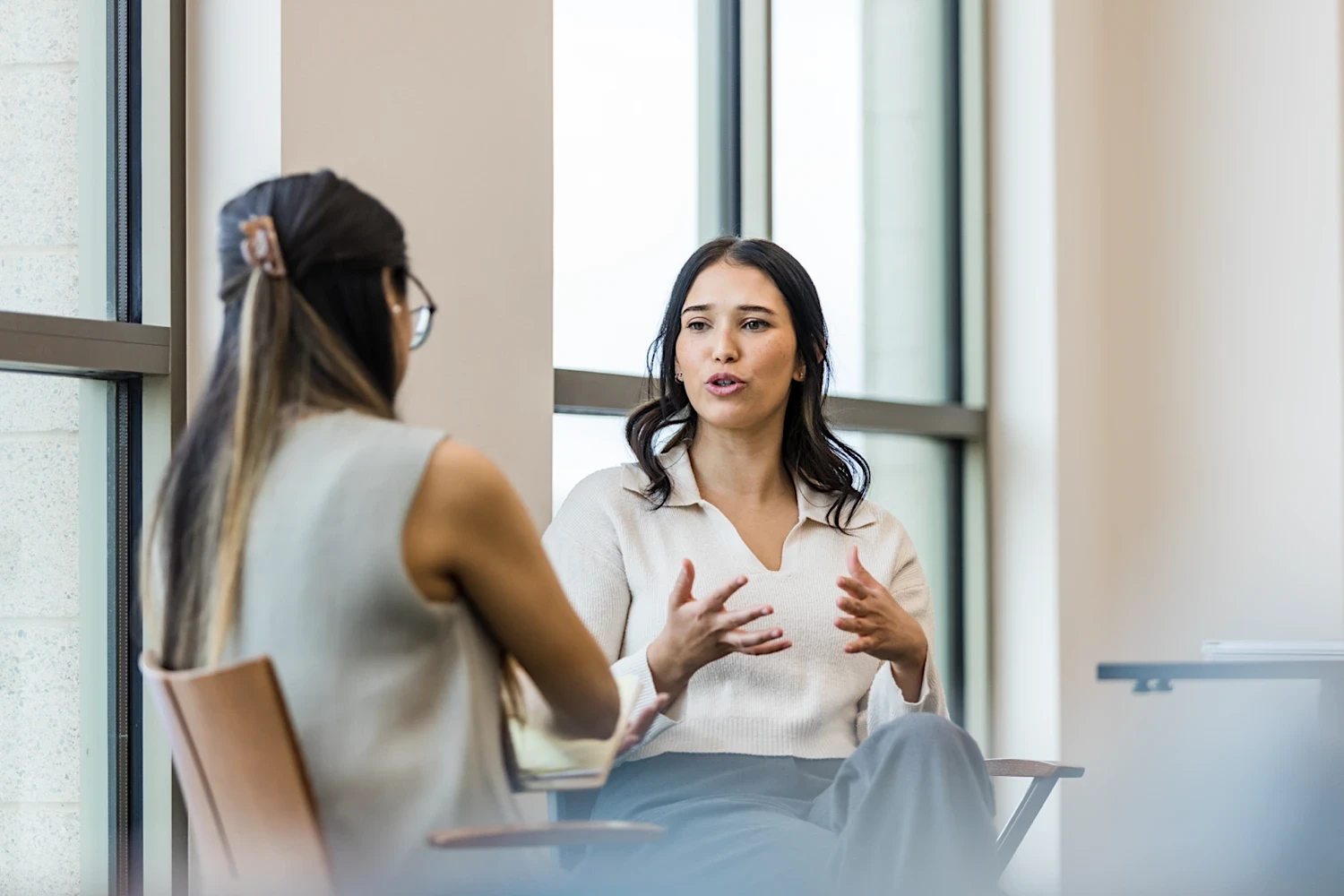 Two legal professionals seated in conversation in a modern office, discussing work collaboratively during a professional meeting.