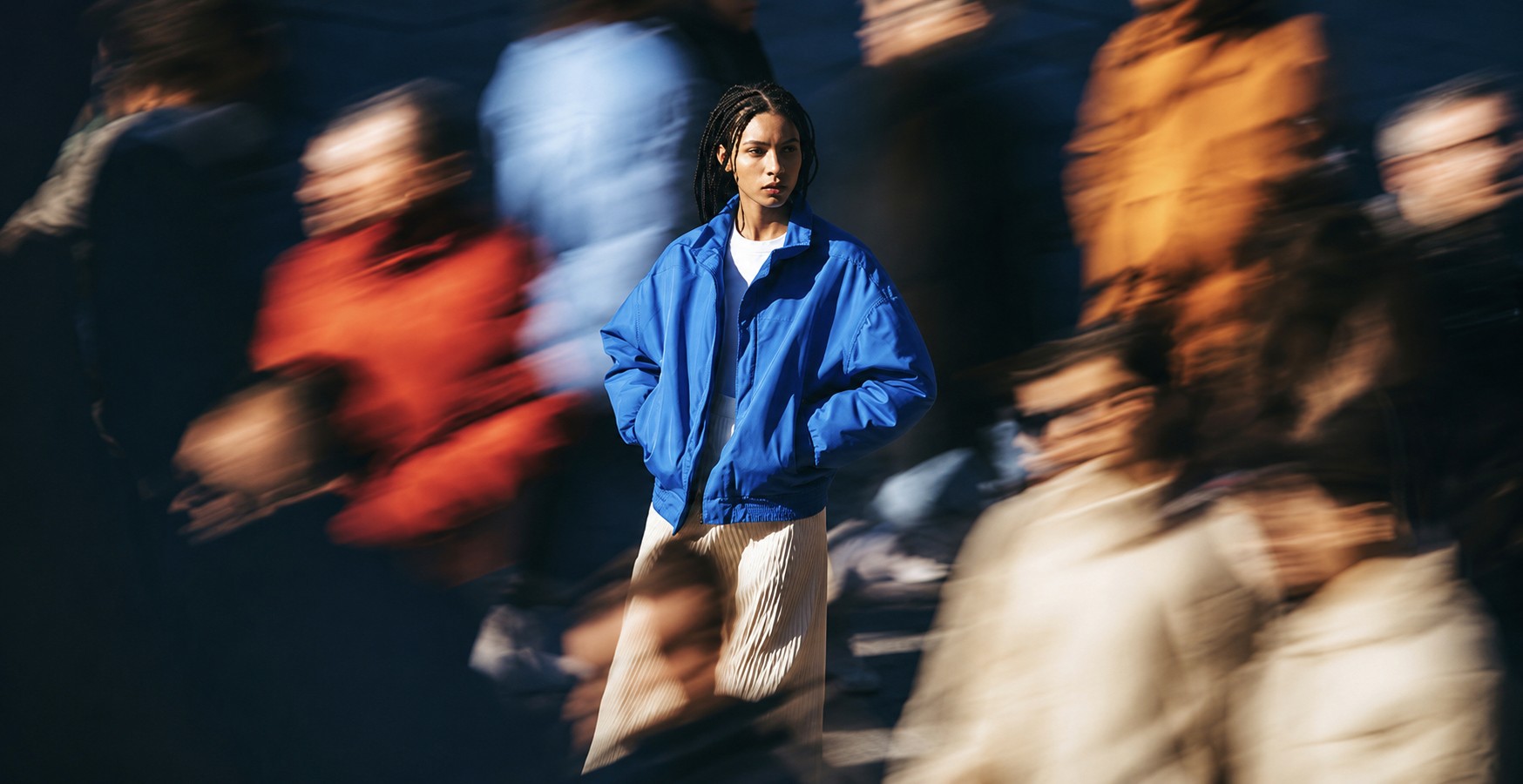 A woman stands still amid a blurred, moving crowd