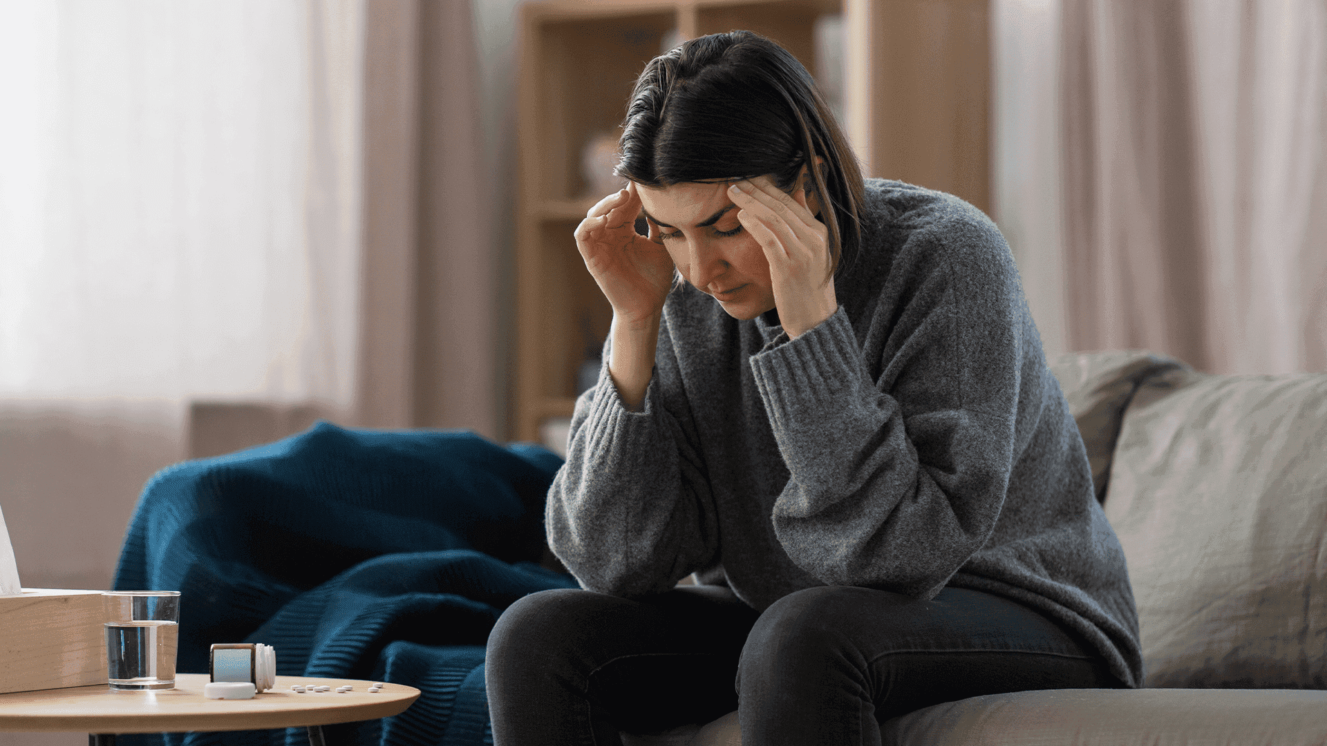 Woman sitting on a couch experiencing high-functioning anxiety and feeling overwhelmed