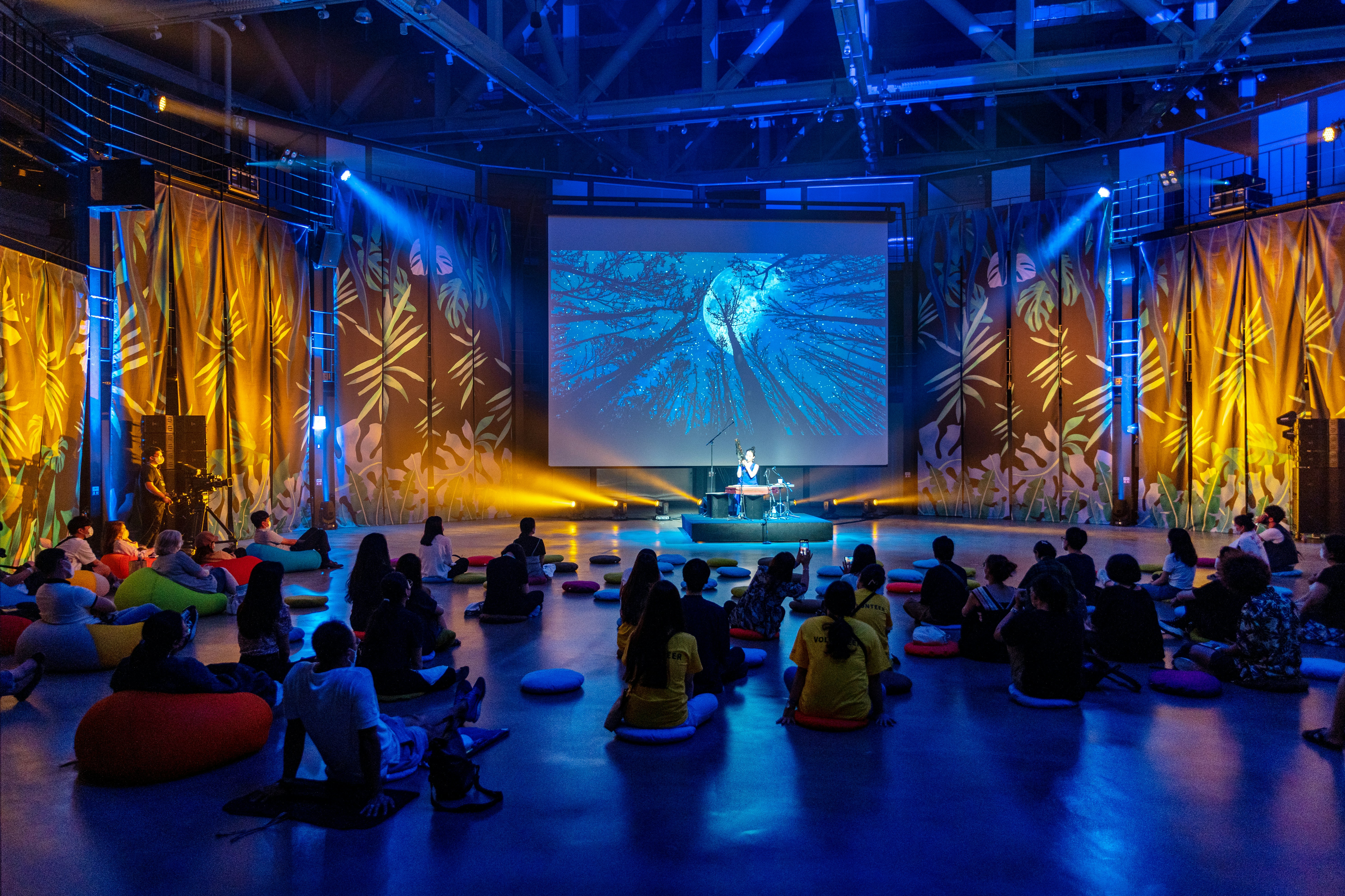a group of people sitting on bean bags in front of a stage