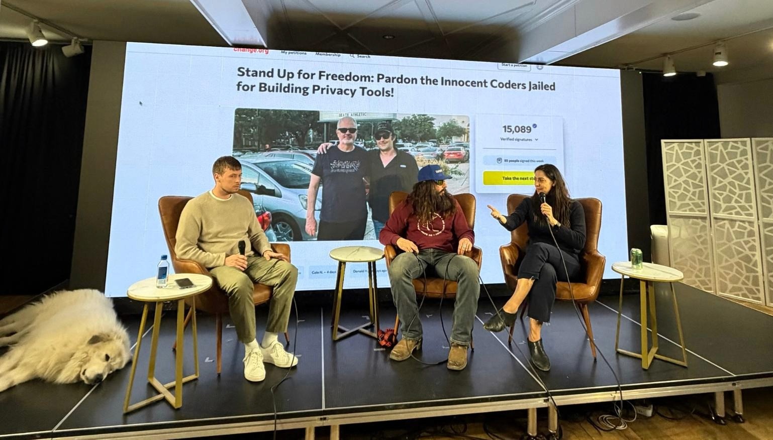 Panelists Zack Cohen, Econoalchemist, and Renata Rodrigues seated in leather chairs on stage at Bitcoin Park Nashville, engaged in a discussion.