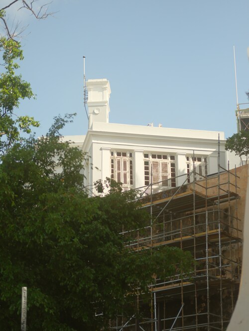 White building with scaffolding and trees