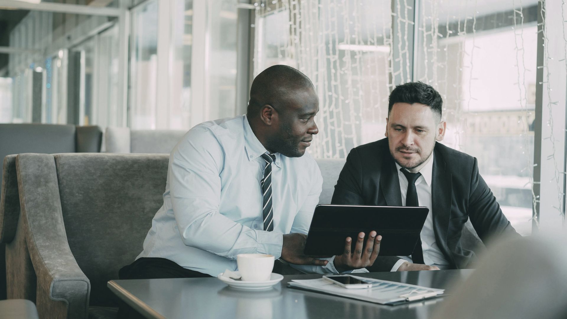 Two business executives analyzing real-time data visualizations on a digital tablet