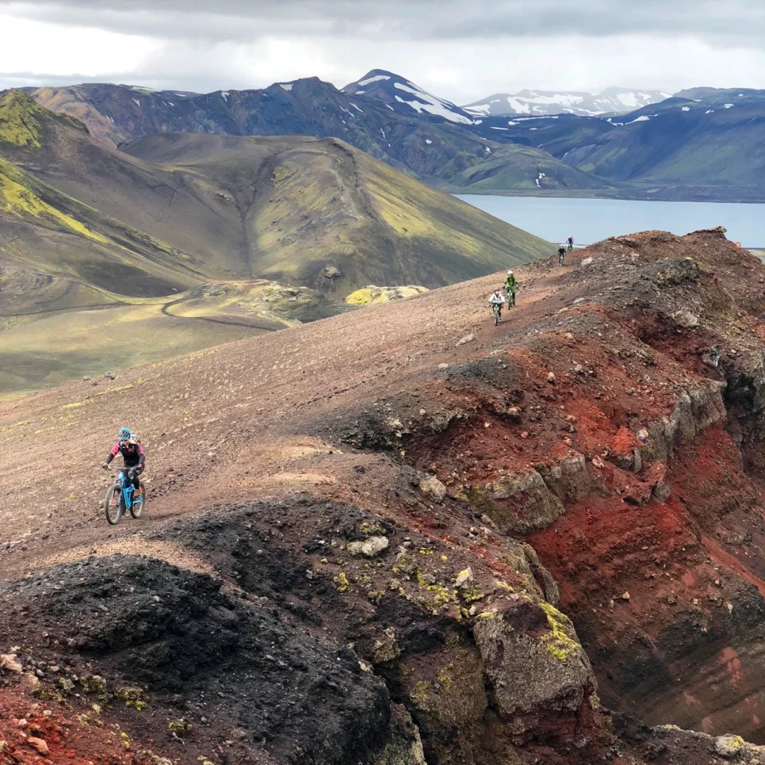A man rides a bike on red lavarocks with big landscapes in backround
