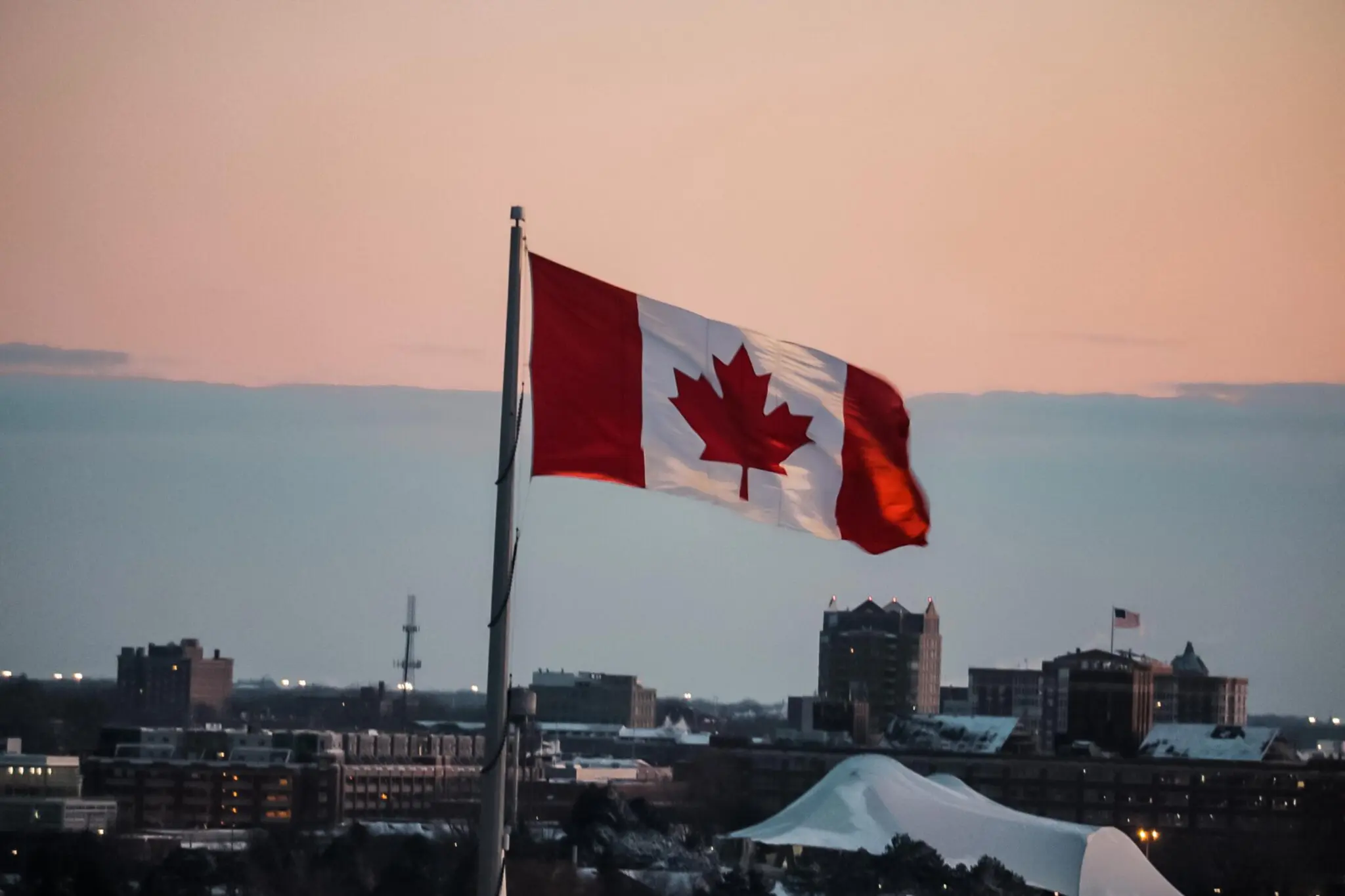 Waving Canadain flag standing high over a bubbling city in the background 