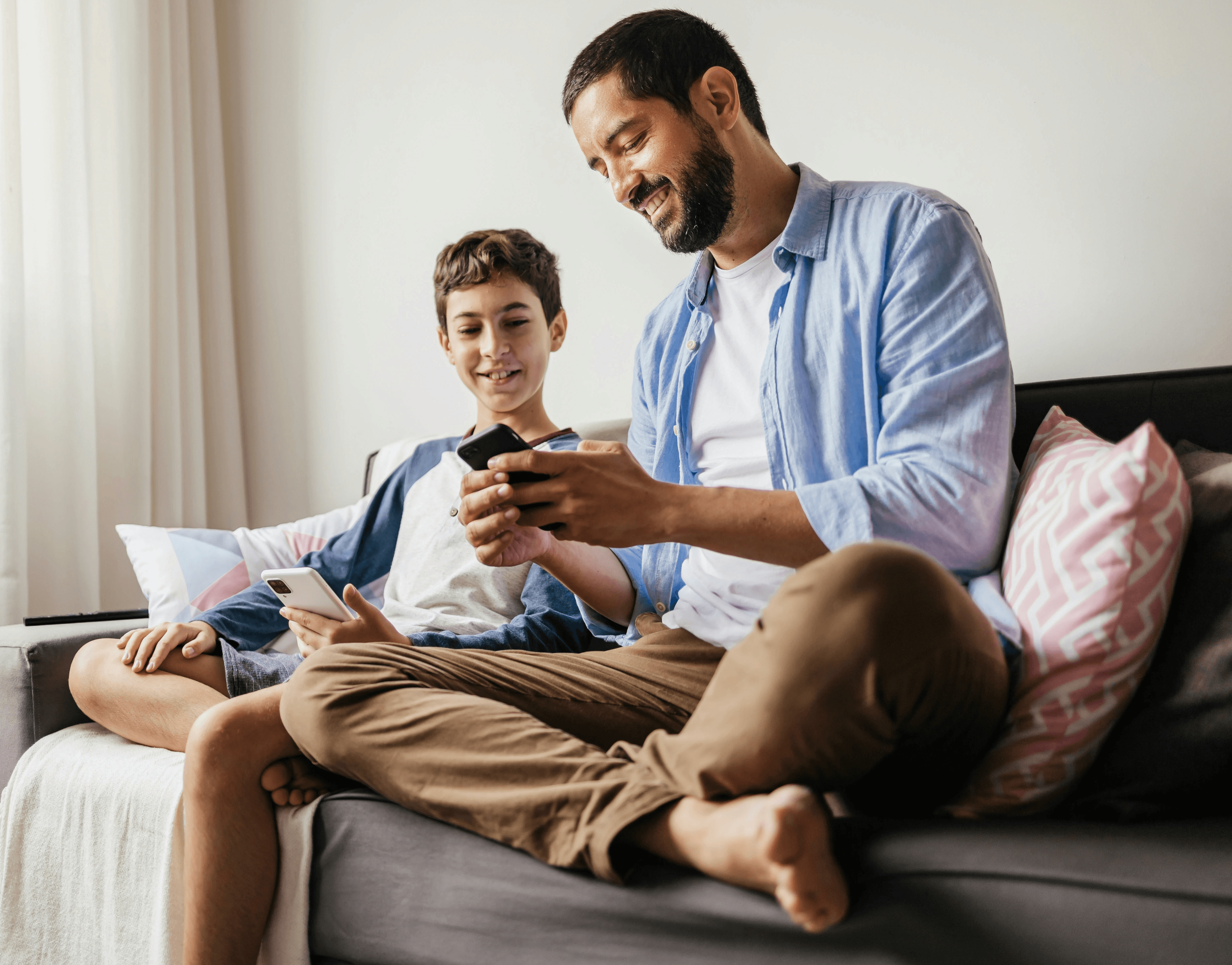 Grandfather and grandson reading a book together on couch.