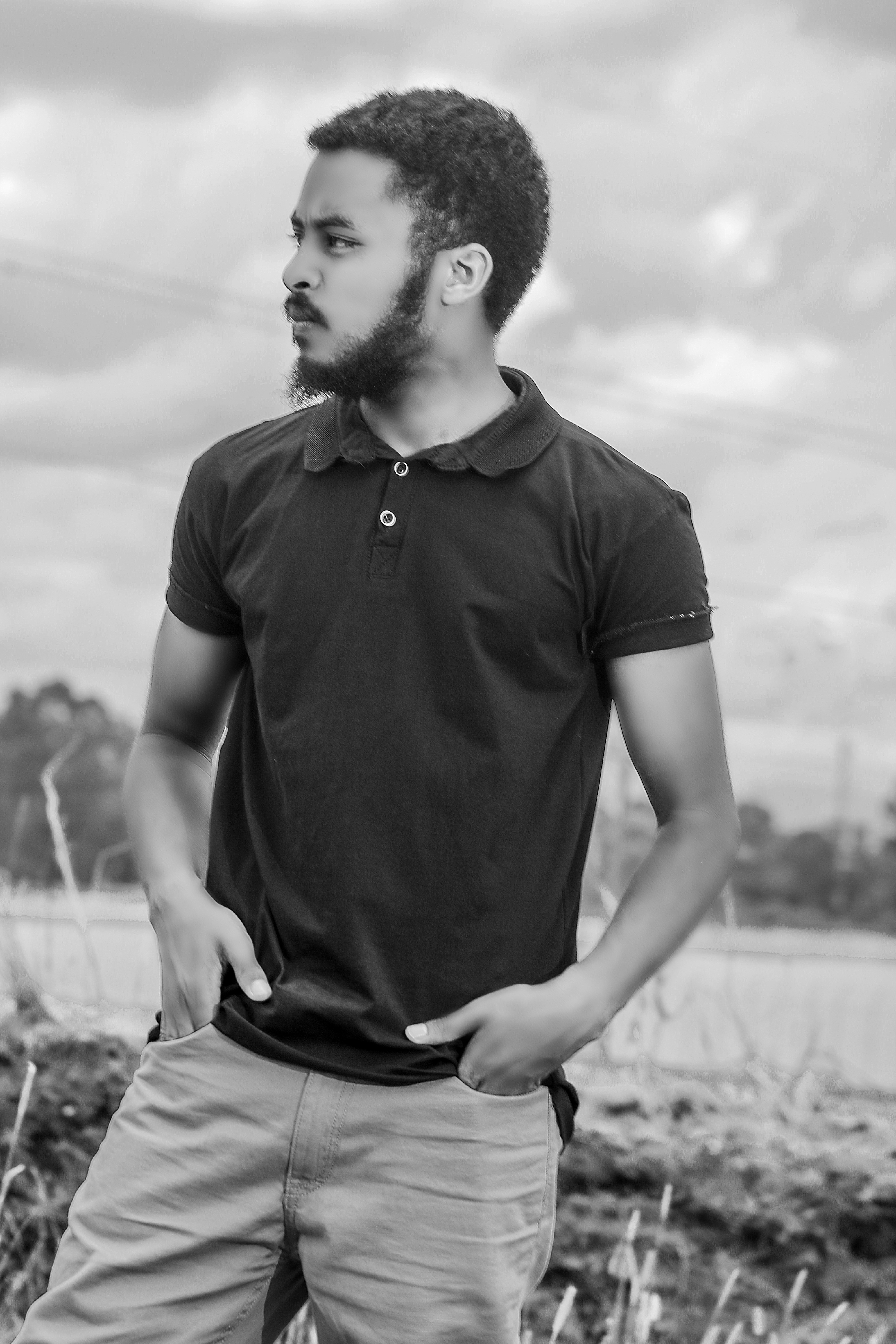a man standing in a field with his hands in his pockets