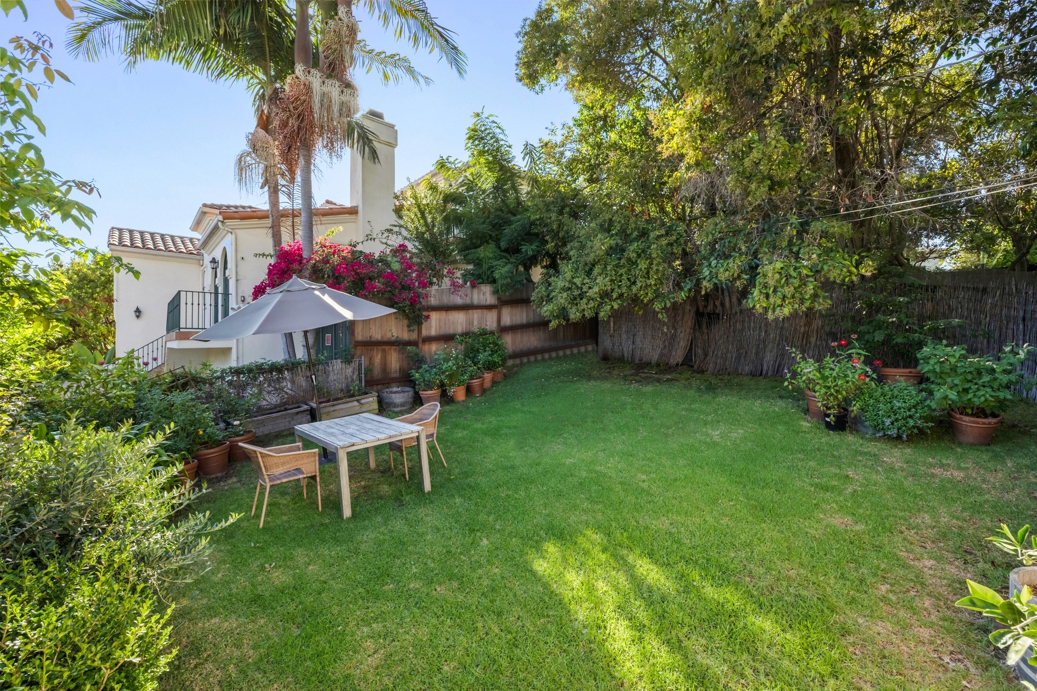 A lush garden scene at 10301 mississippi, featuring green grass, trees, and a small table set in a sunny outdoor space.