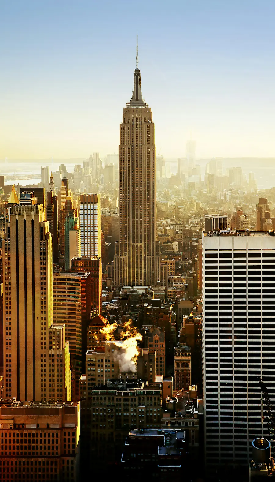 Empire State Building towering over Midtown Manhattan in New York City at golden hour.