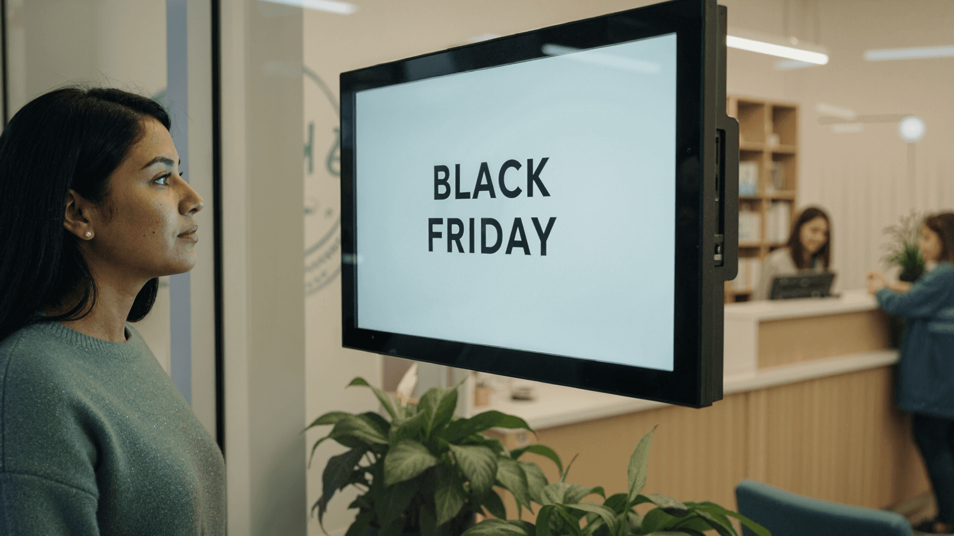 Mulher observa uma tela com a mensagem “Black Friday” em um ambiente corporativo. A imagem pode ilustrar campanhas promocionais para clínicas que utilizam a plataforma Tivita, destacando oportunidades de otimizar a gestão durante períodos de alta demanda.
