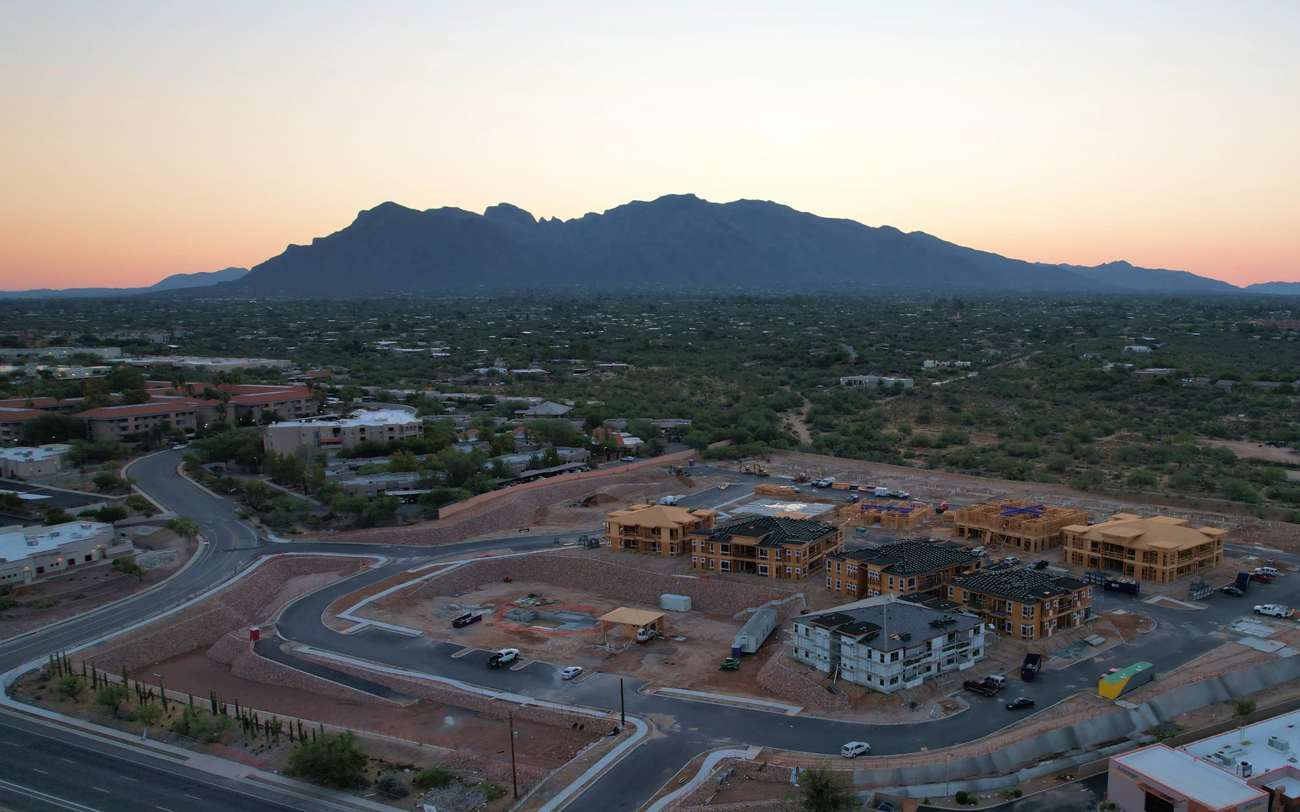 Aerial view of a construction site surrounded by mountains, showcasing ongoing development against a natural backdrop.