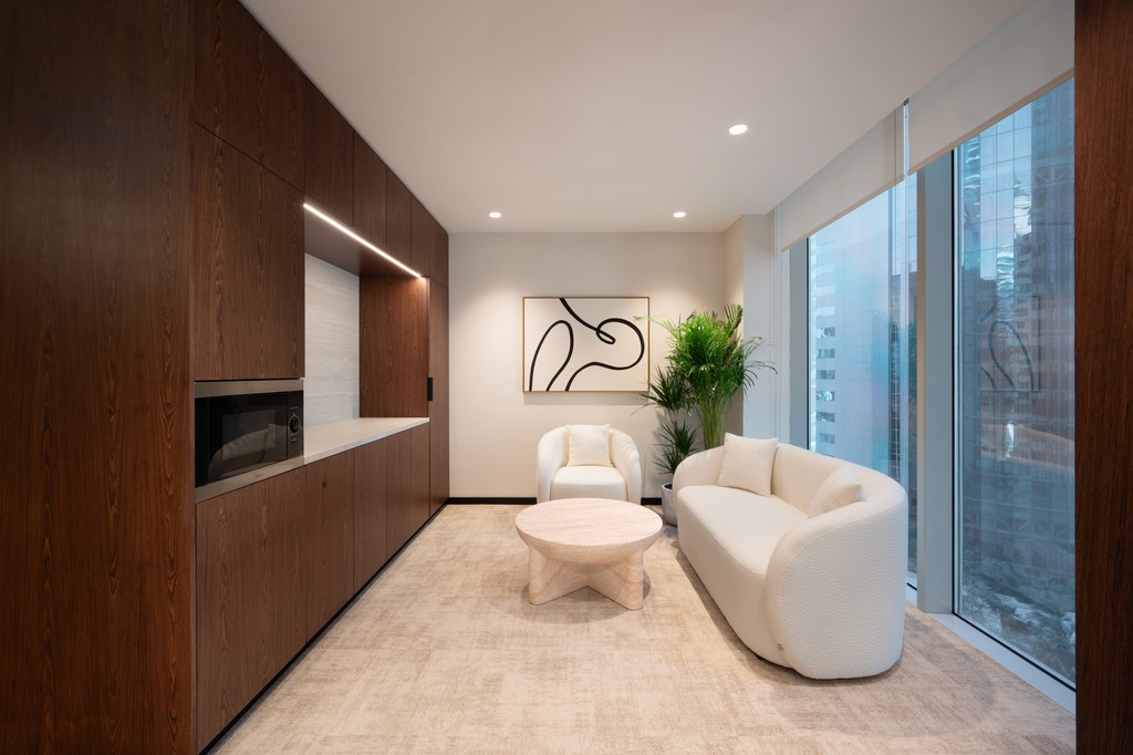 Enclosed meeting room with sound-dampening glass walls, round wooden table, and clean minimalist design.