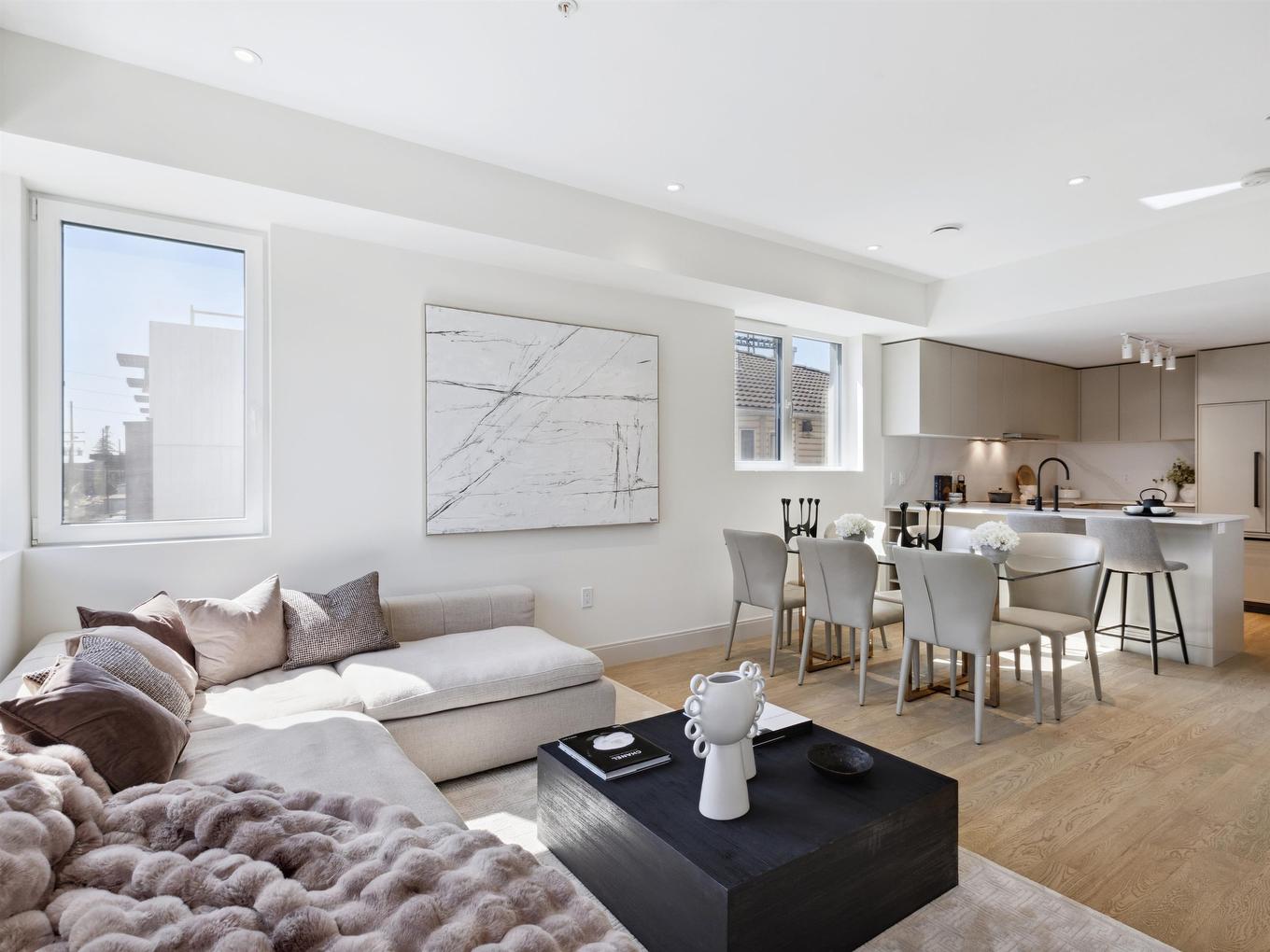 Bright, modern living space with a sofa, coffee table, and dining area in an open-concept design.