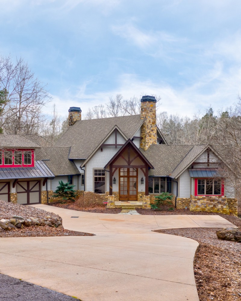 A smiling woman with her arms crossed, standing against a dark green background. She has long, dark hair.