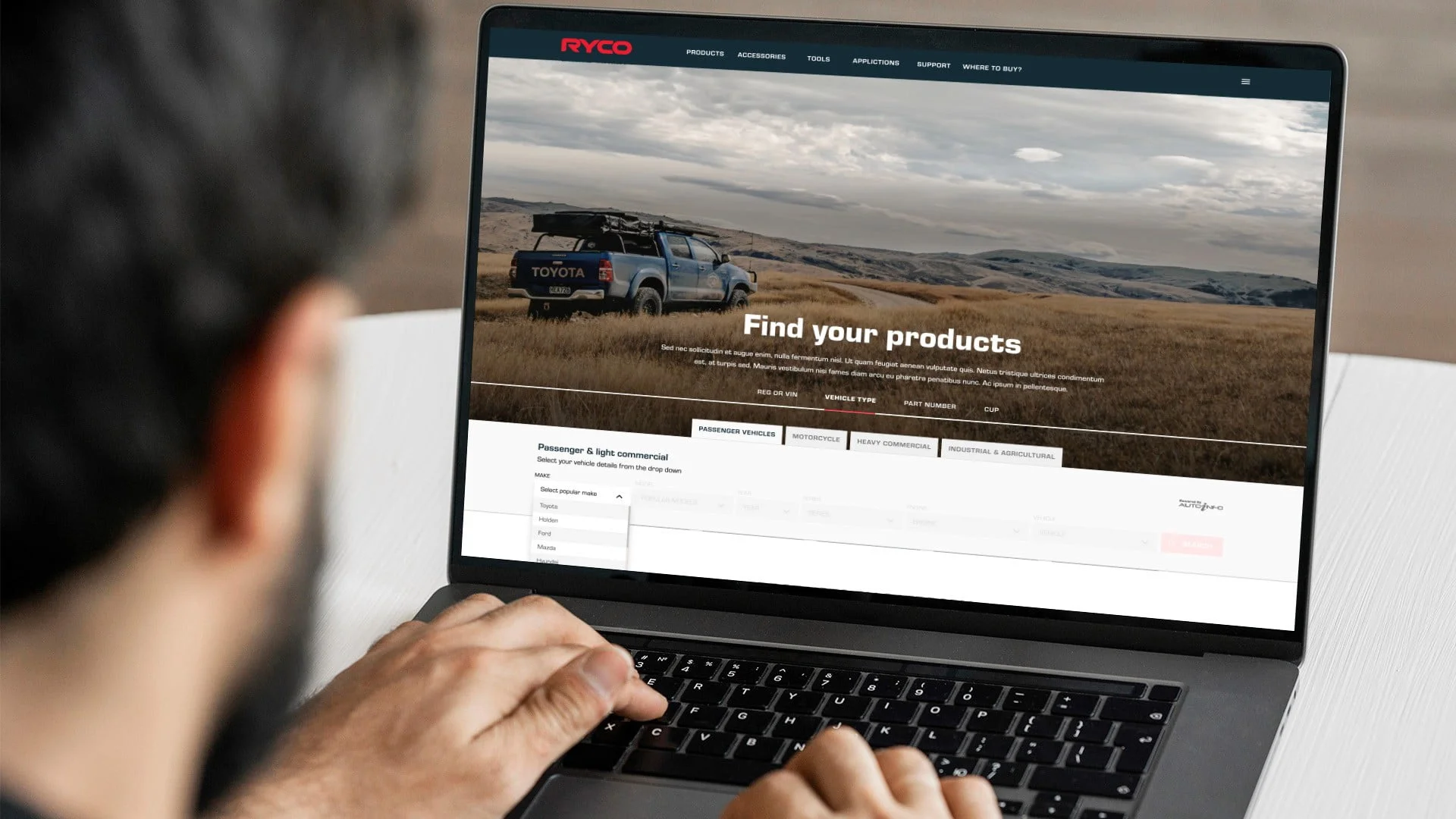 Laptop showing the Ryco website 'Find your products' page over a Toyota 4WD in dry grassland, with a vehicle filter selector