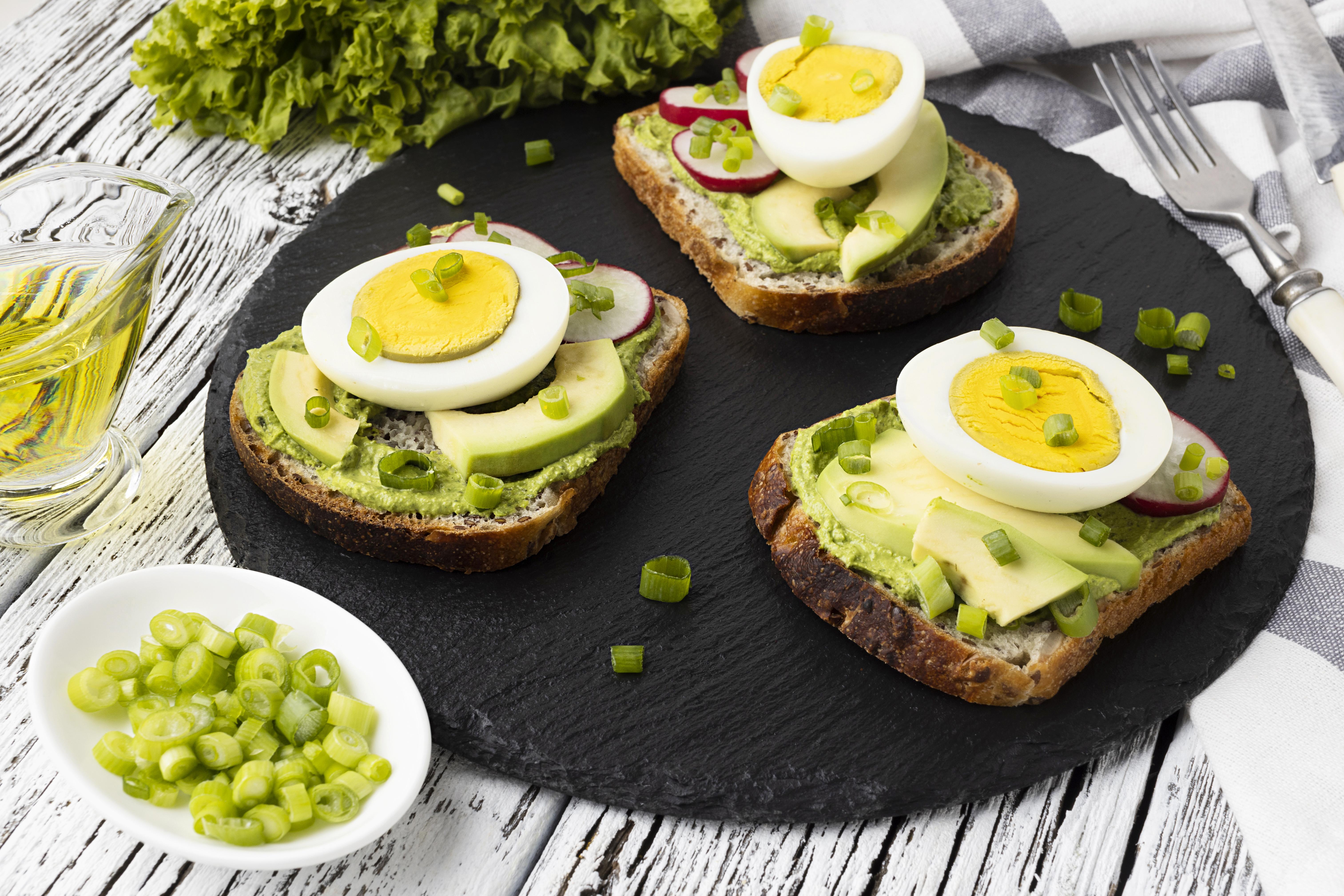Sliced avocado with two halved hard-boiled eggs on a wooden plate