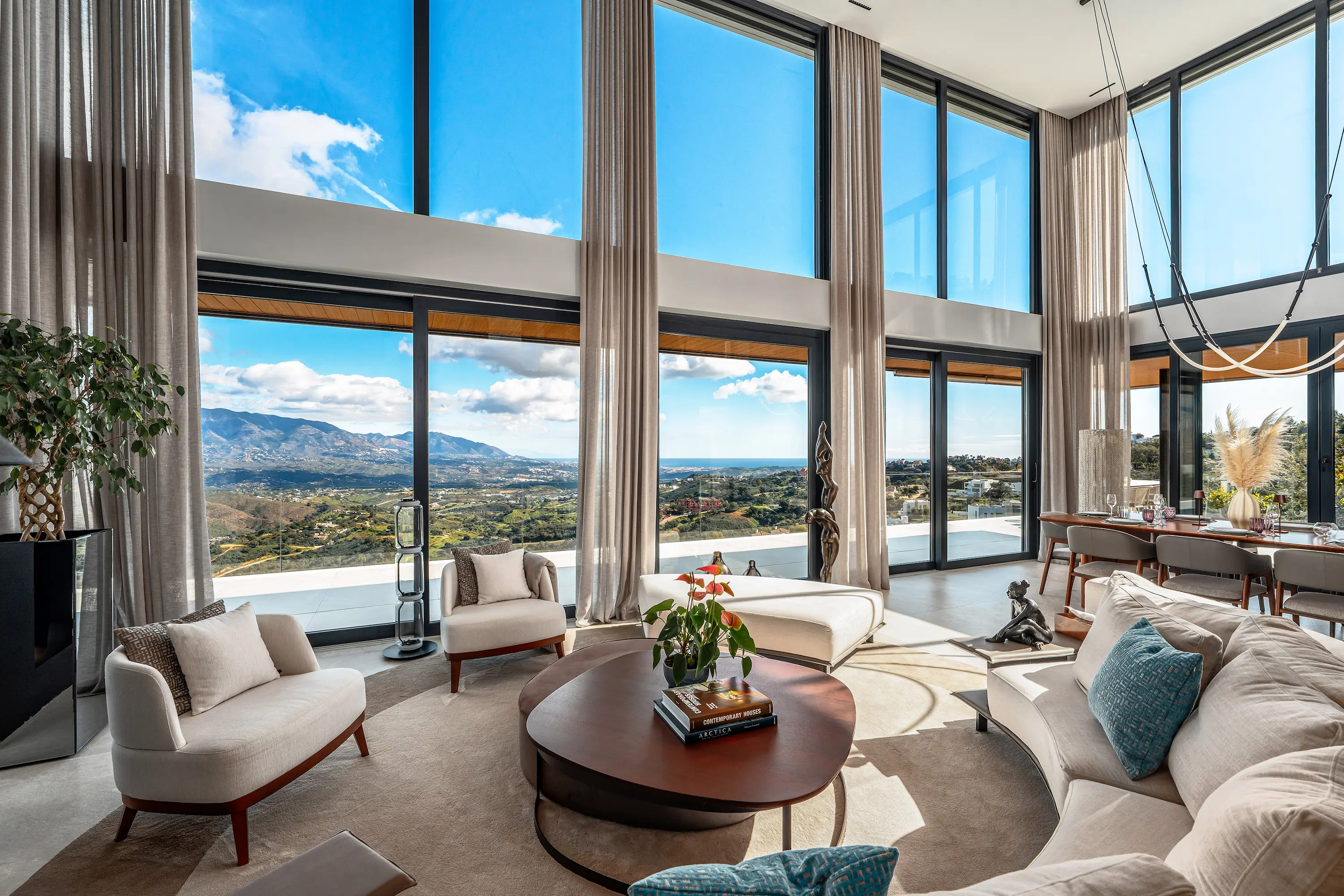 Villa Vista Marbella dining area with panoramic glazing, set wooden table, and hillside views