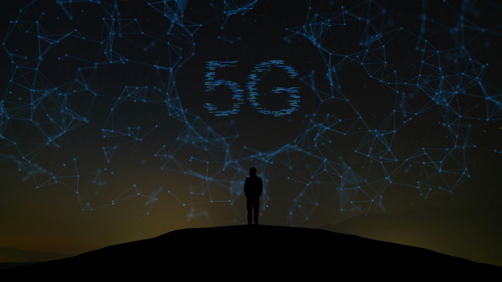 A silhouetted figure stands on a hilltop beneath a night sky filled with glowing blue network lines and nodes, with "5G" prominently displayed, symbolizing the connectivity and advancements of 5G technology.