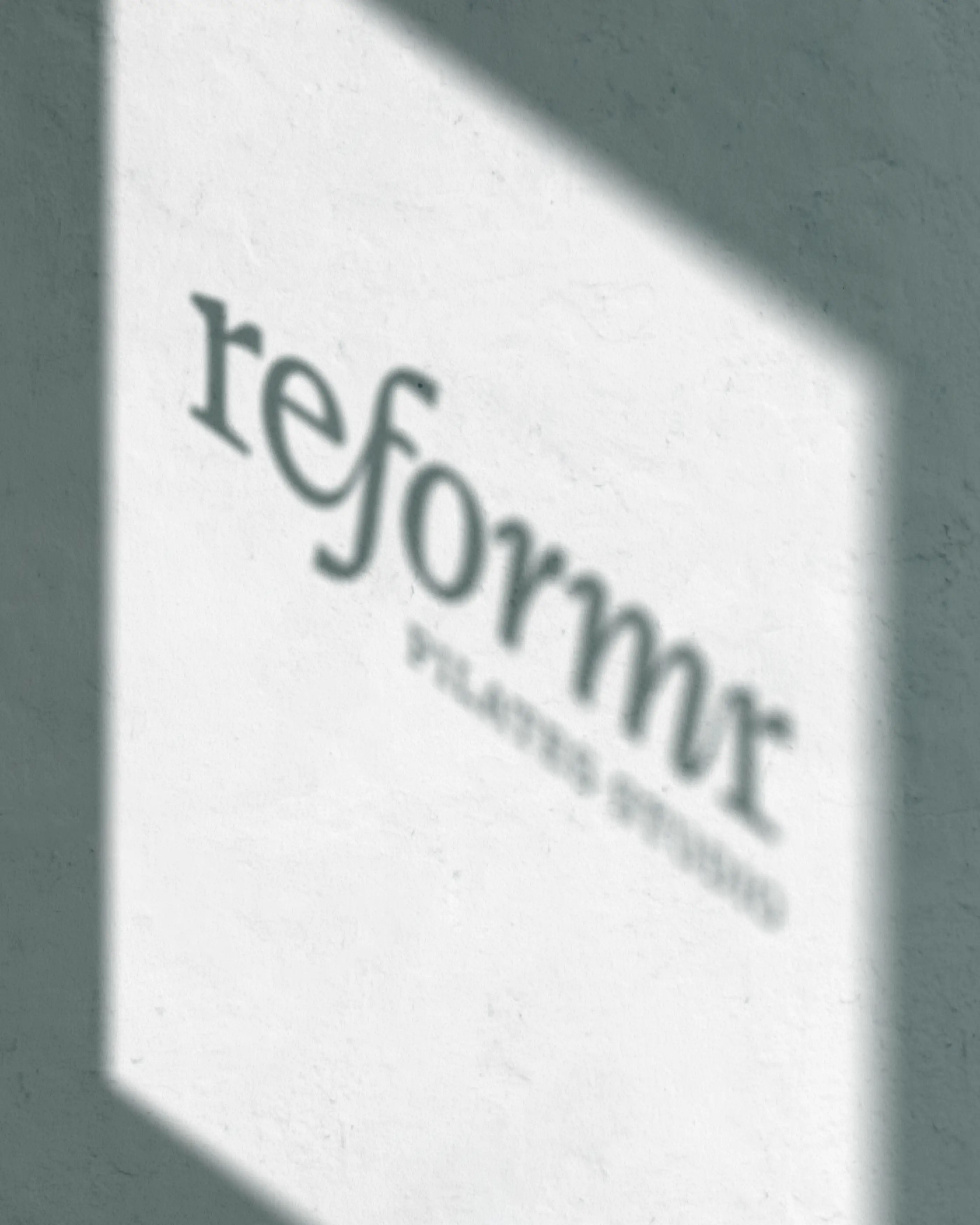 Reformr Pilates Studio logo casted as shadow on wall