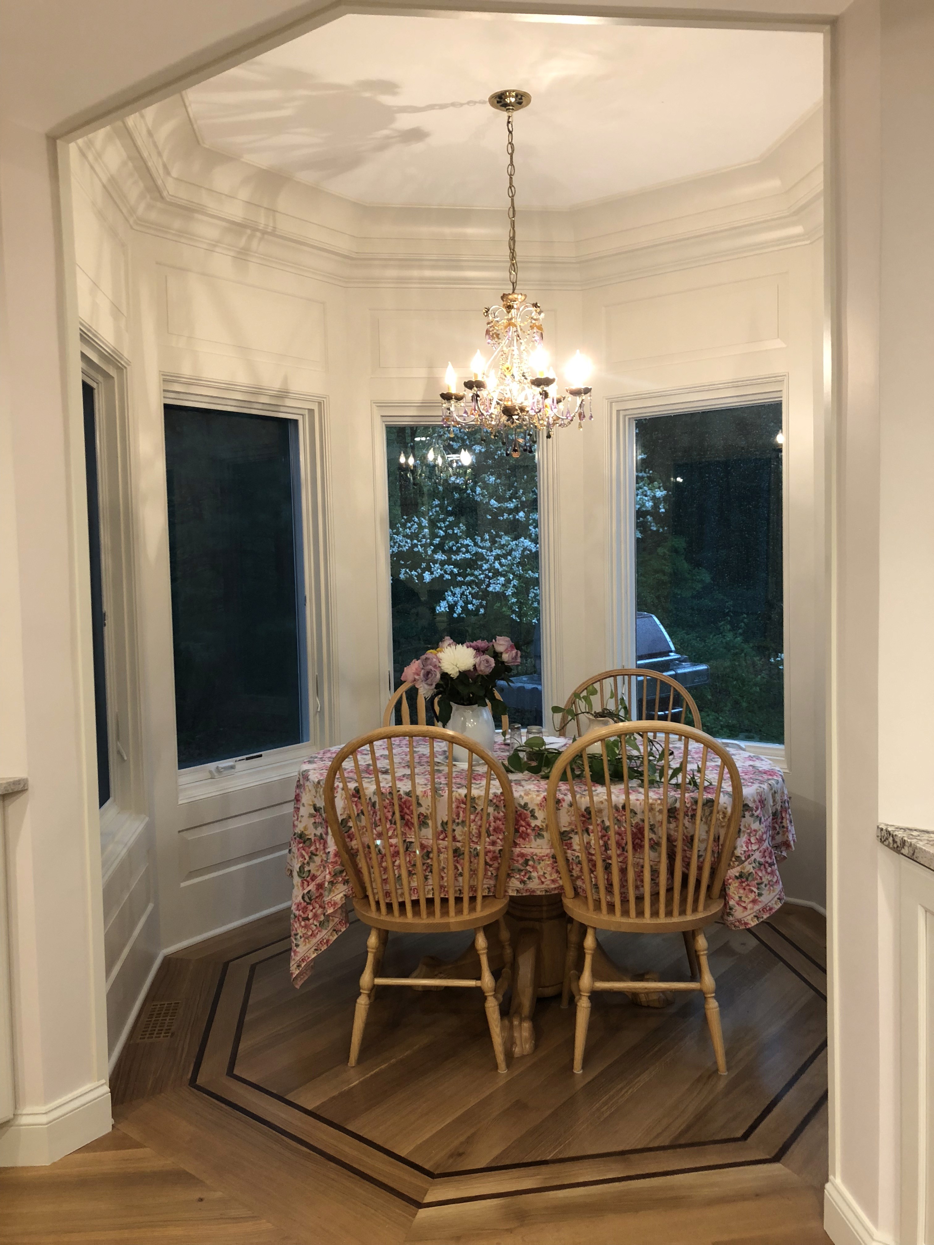 Finished dining area with bay windows, chandelier, and custom trim work in a renovated home interior