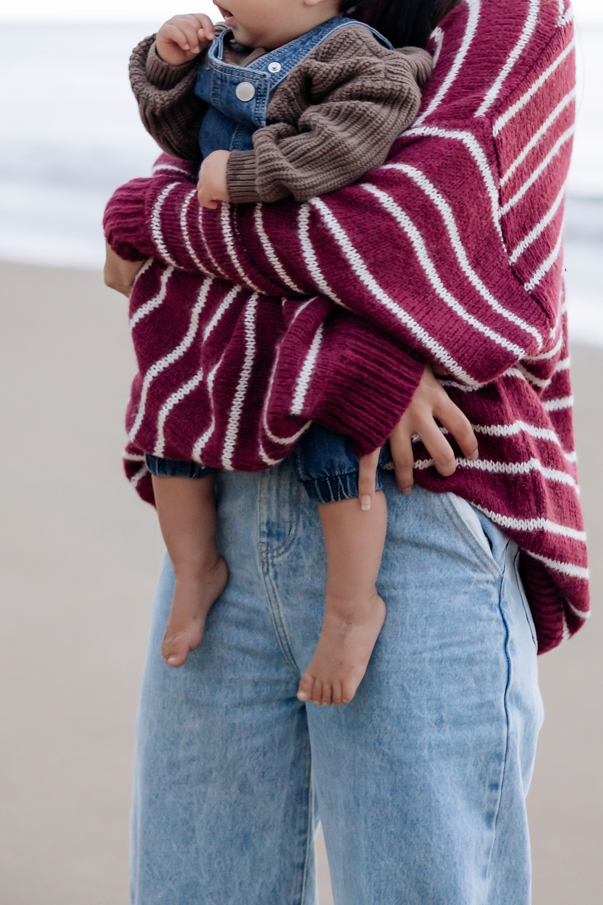Mother cuddling her child during a winter family photography session at Mackay beach