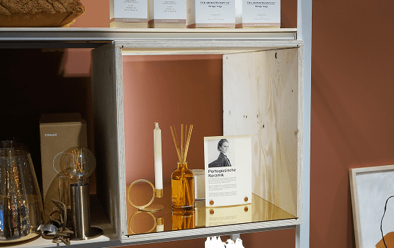 Detail eines Holzelements, das als modularer Einsatz in das weiße Metallregalsystem des micasa Experience Stores integriert wird.