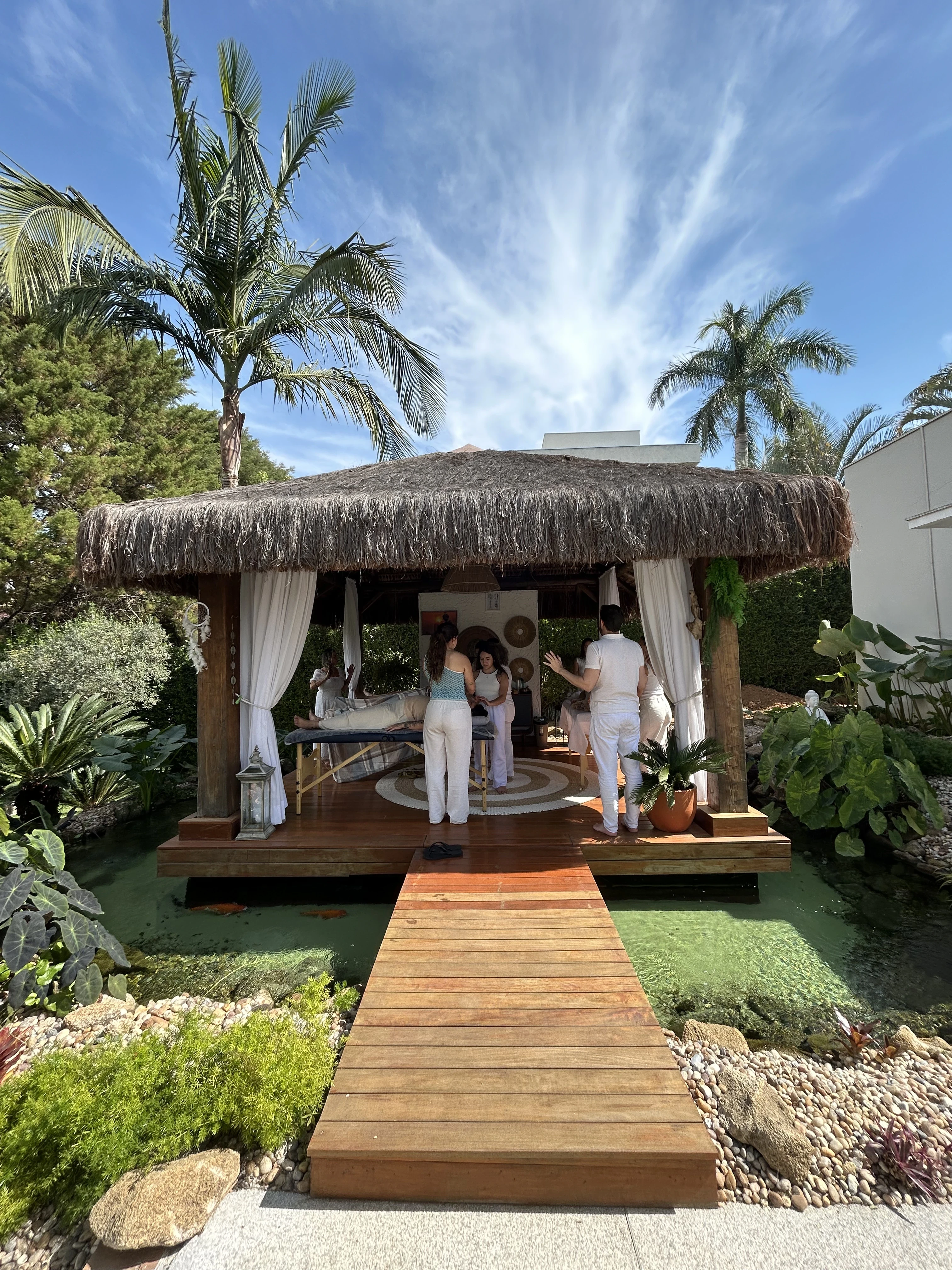 A woman sits cross-legged with eyes closed, wearing a white blouse and a long purple skirt, looking serene.