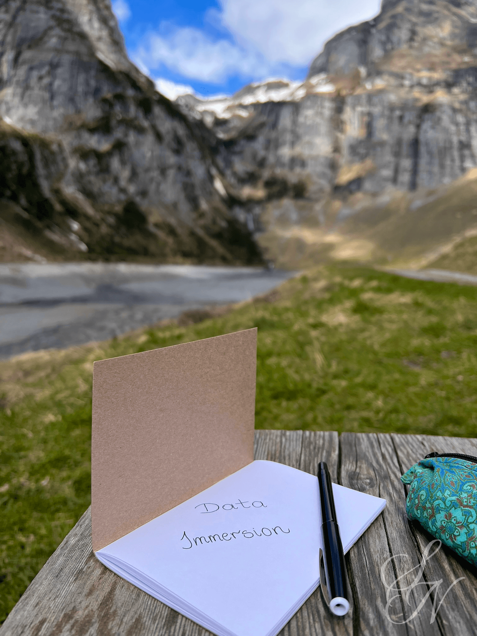 A notebook with a title page reading 'Data Immersion' on a bench at Pigniu Lake in the Swiss mountains.