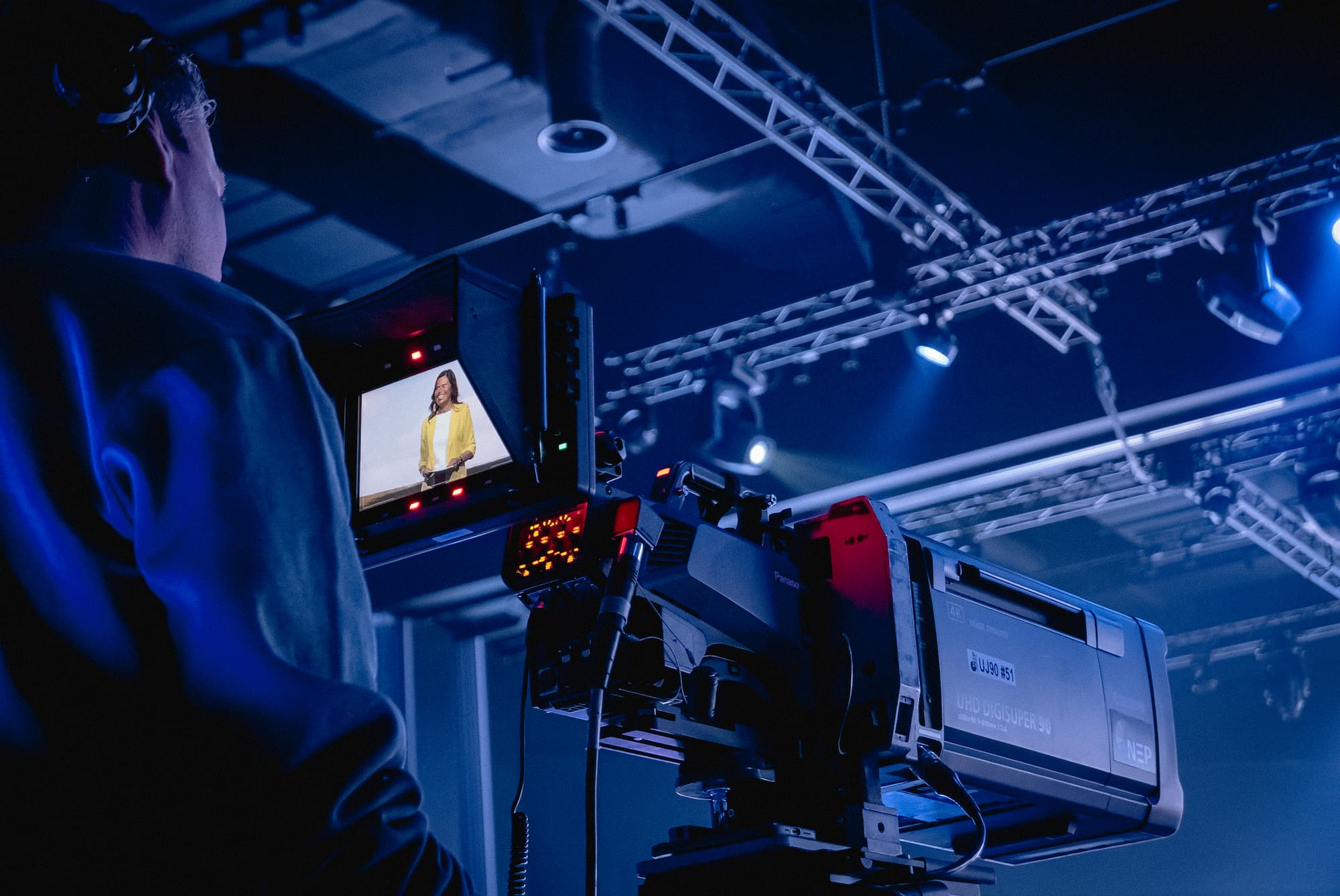 A camera man filming a woman on a large camera