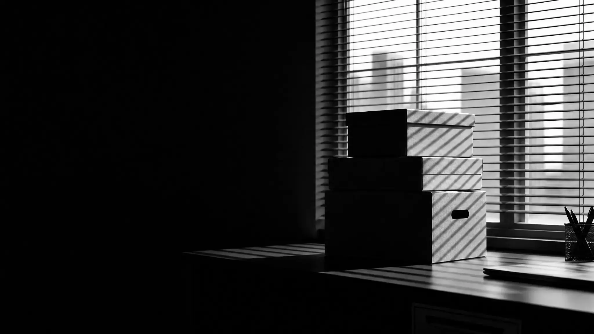 Cartons de rangement empilés devant une fenêtre de bureau, illustrant les situations de licenciement sans cause réelle et sérieuse.