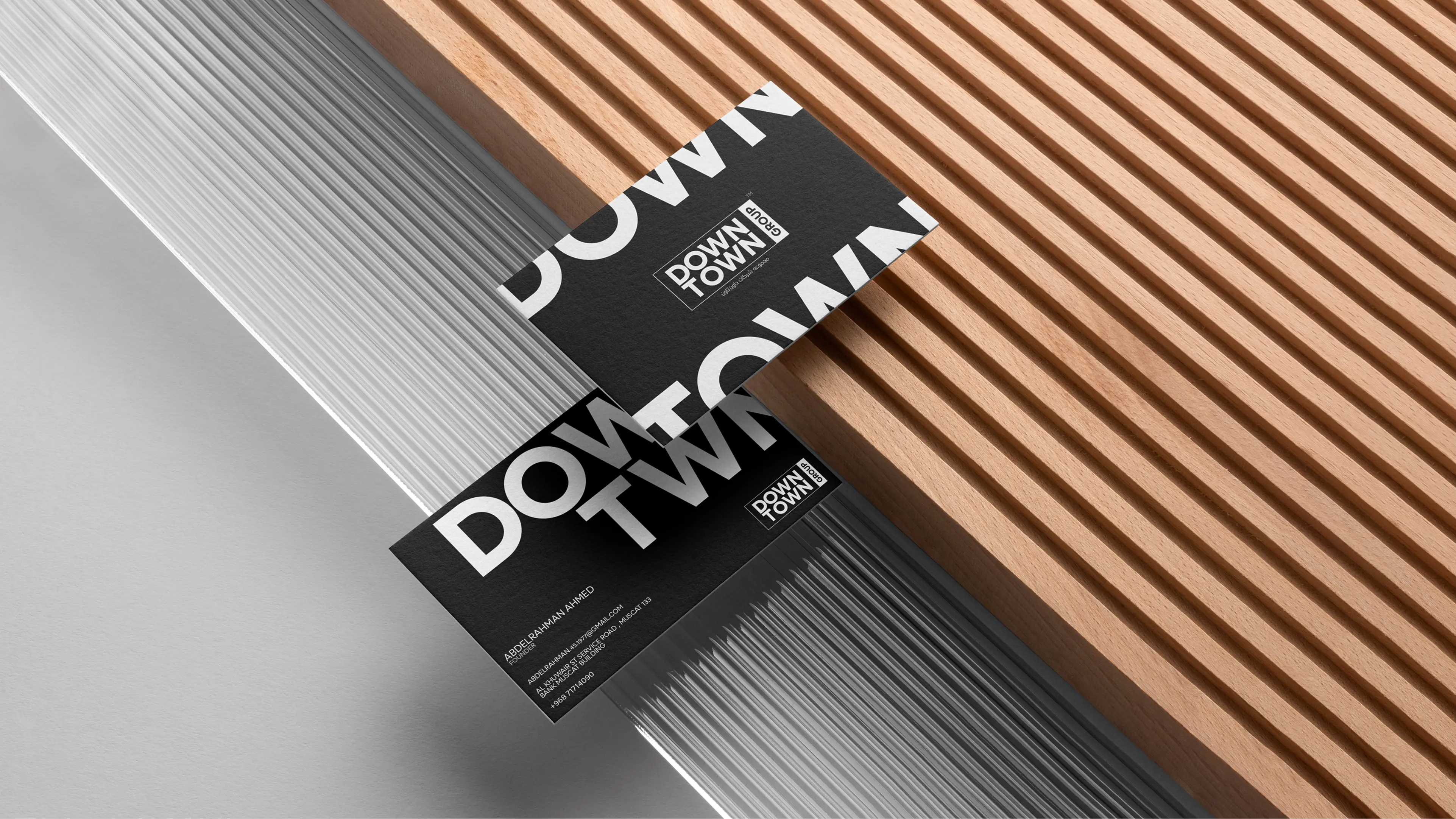 Downtown Group premium black business cards with white logo and brand mark displayed on wooden surface