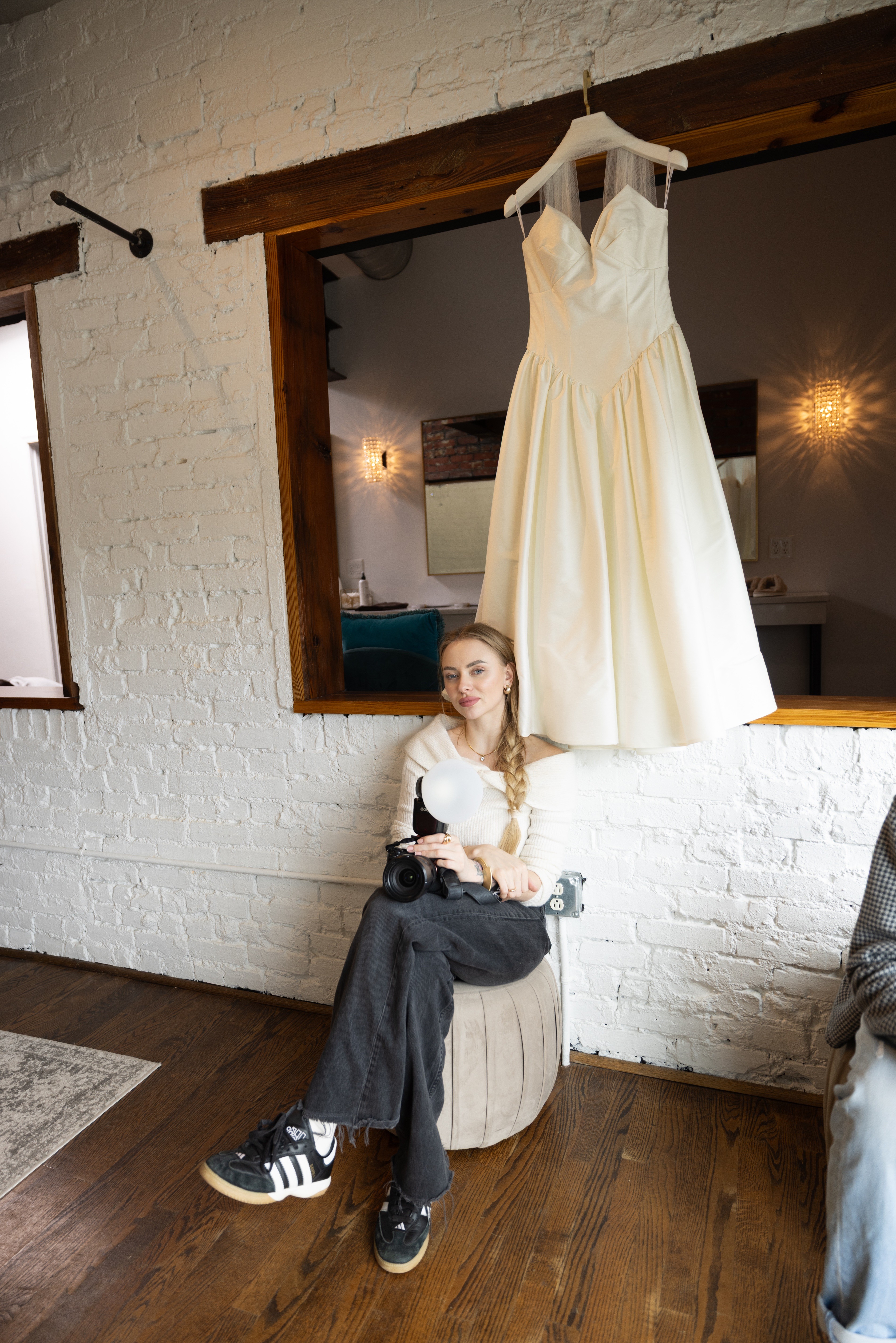 A person with shoulder-length blonde hair wearing a black newsboy cap and a black sweater.