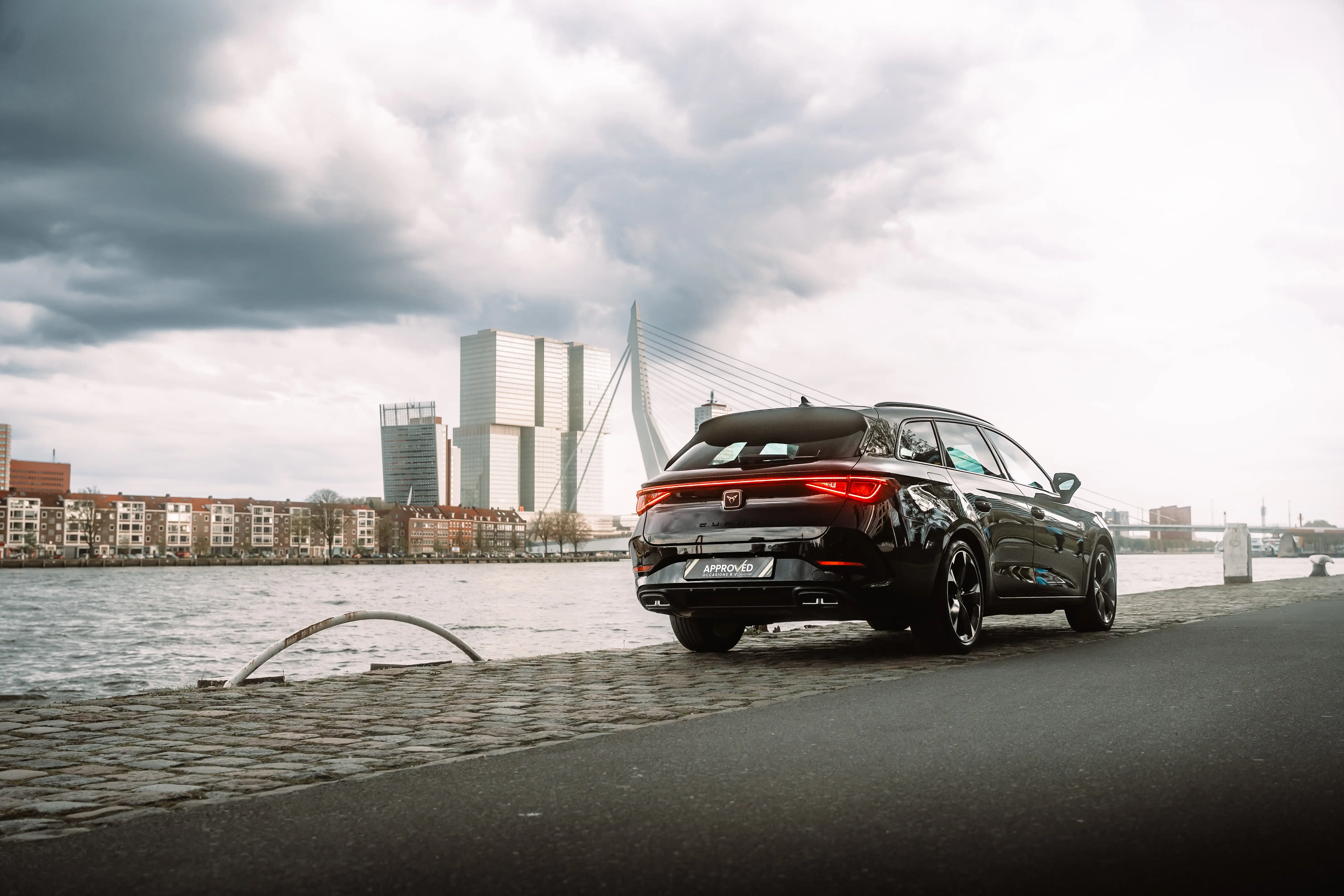 The backside of a Cupra car with the erasmus brug in Rotterdam in the background
