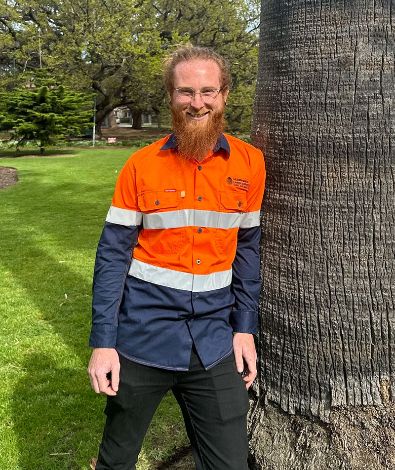 A profile image of James Faull in a professional surveyor uniform in a leafy outdoor setting