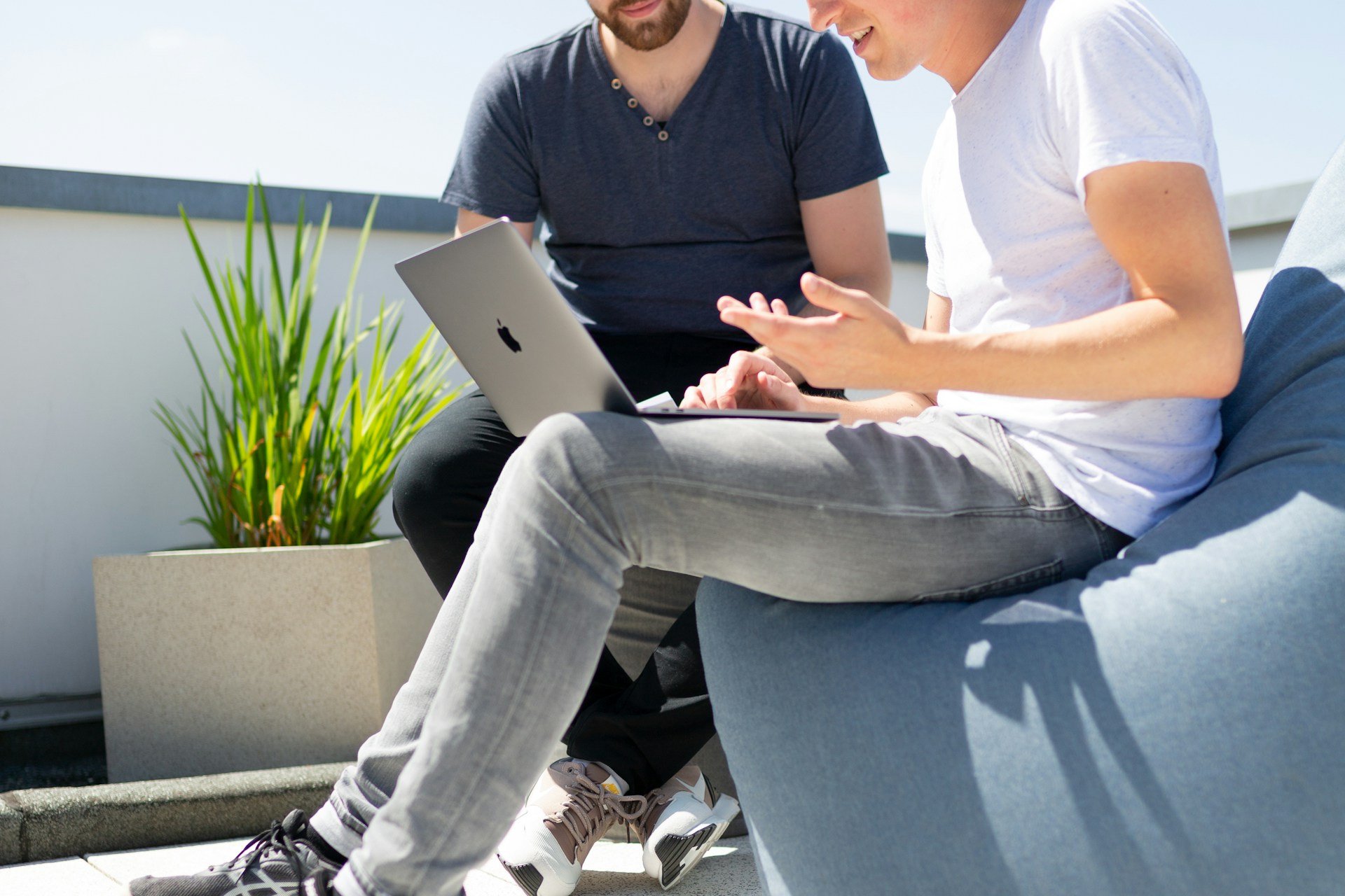 Two Young Men Looking at Laptop sitting outside in the sun