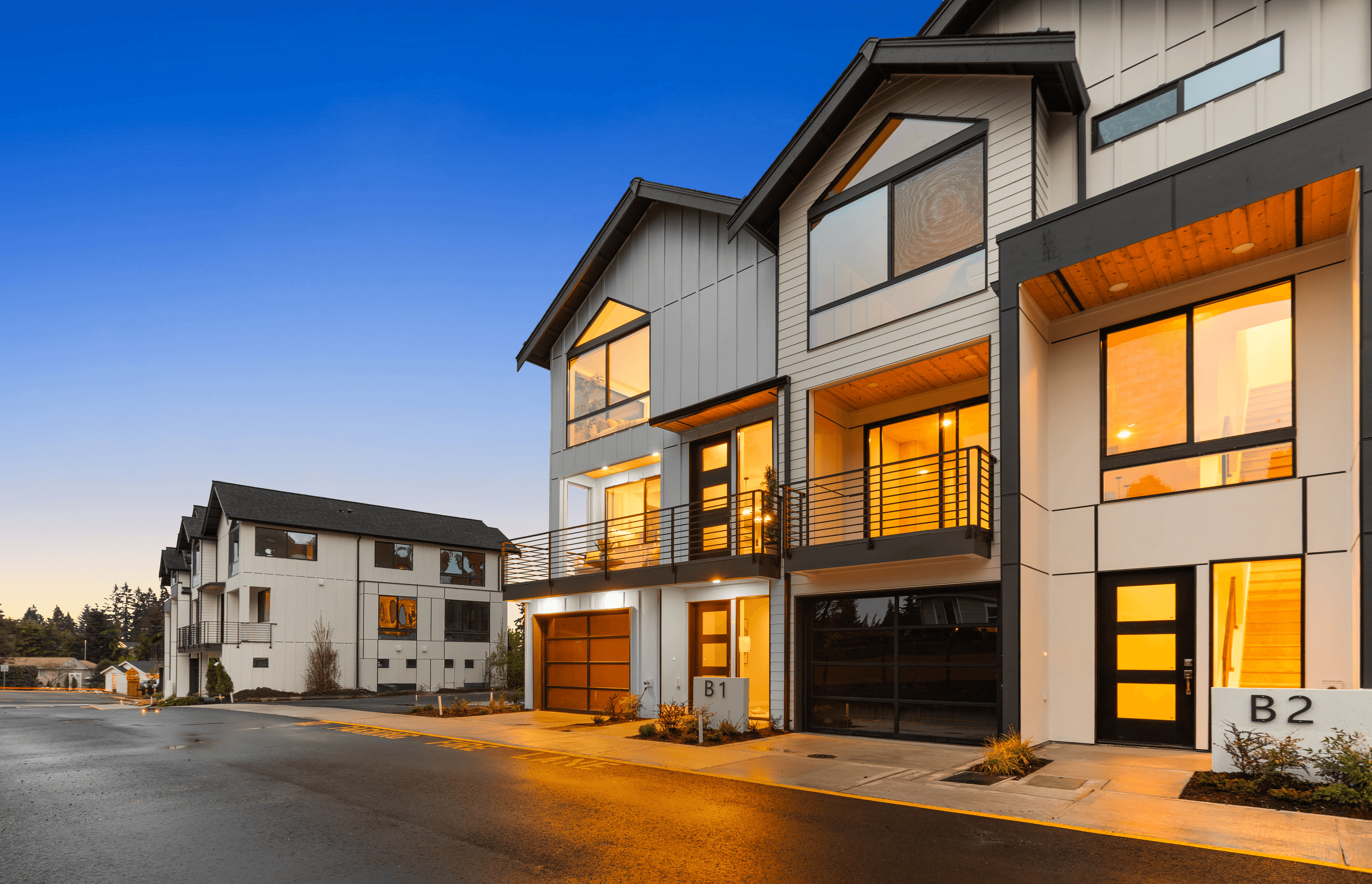 Modern luxury townhomes with illuminated windows and upscale residential community at dusk