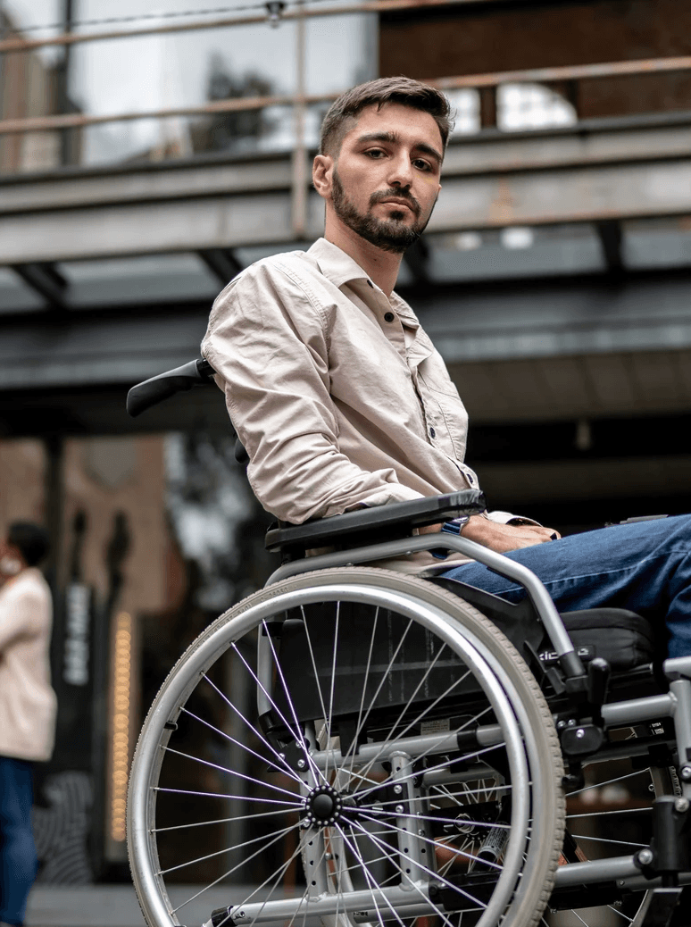 photo of a young man in a wheelchair, outdoors in a plaza