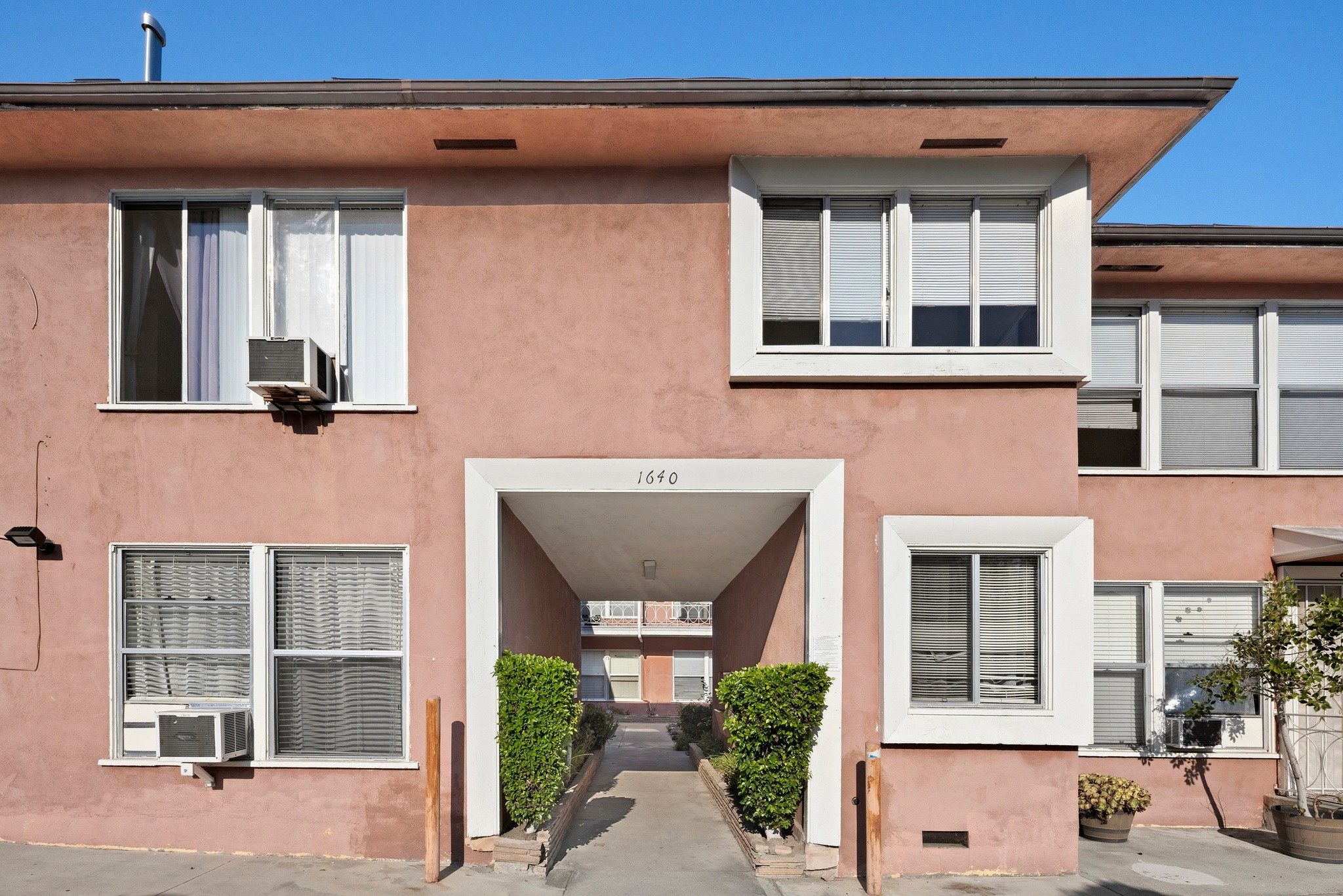 1640 N Harvard building entrance with address number 1640, white trim, peach exterior, and landscaping