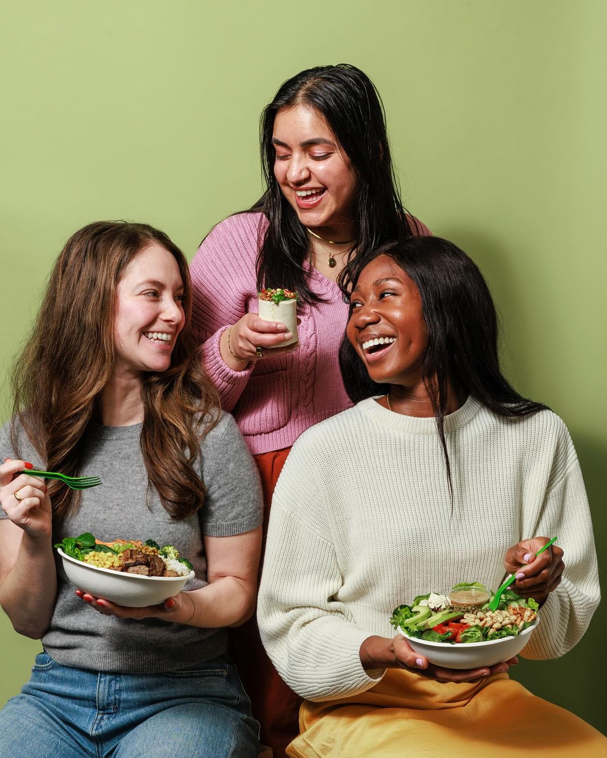 three people sitting in front of table laughing together