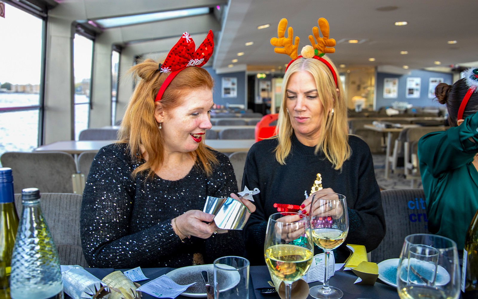 Gjester som nyter en julelunsj på et cruise på Themsen med festlige hodebånd.