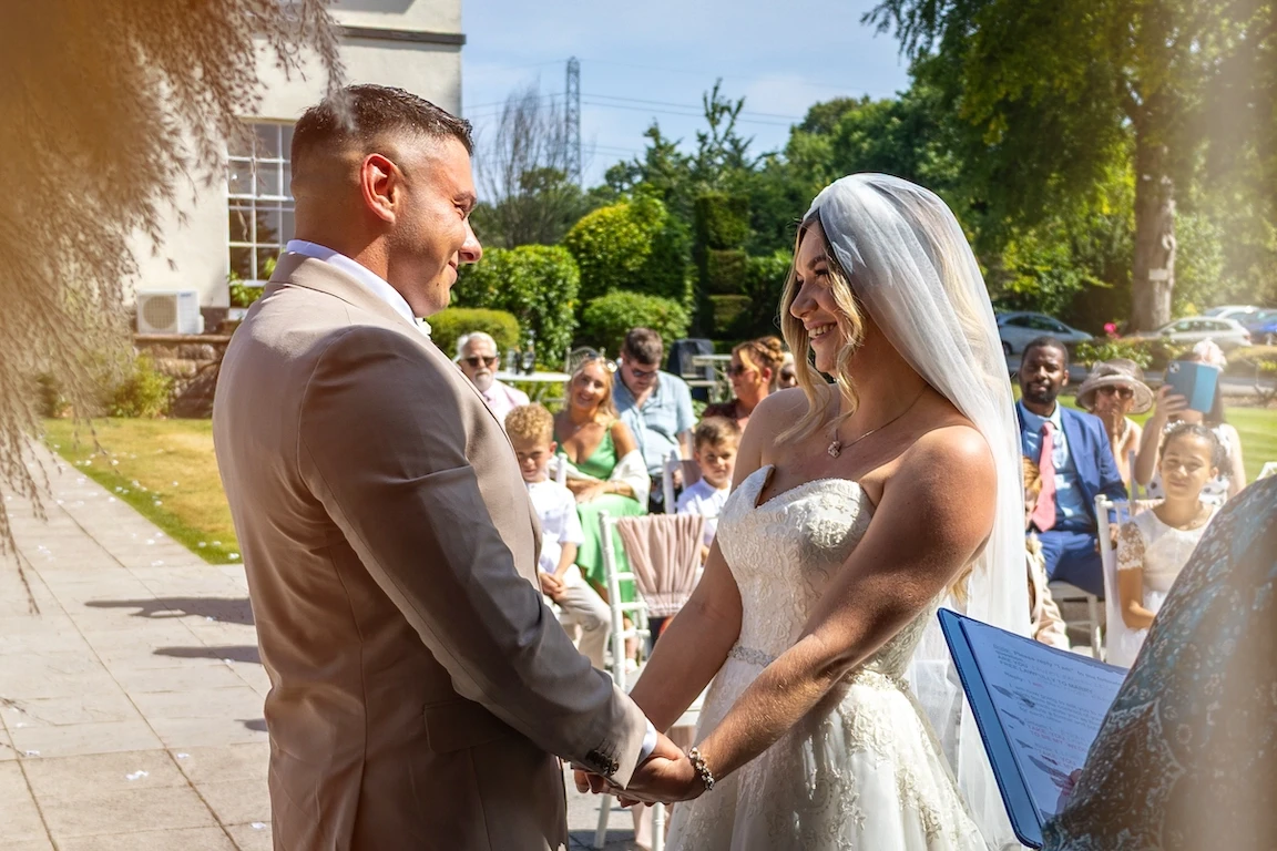 Lauren and Ethan holding hands during their outdoor wedding ceremony at Highfield Hall near Chester