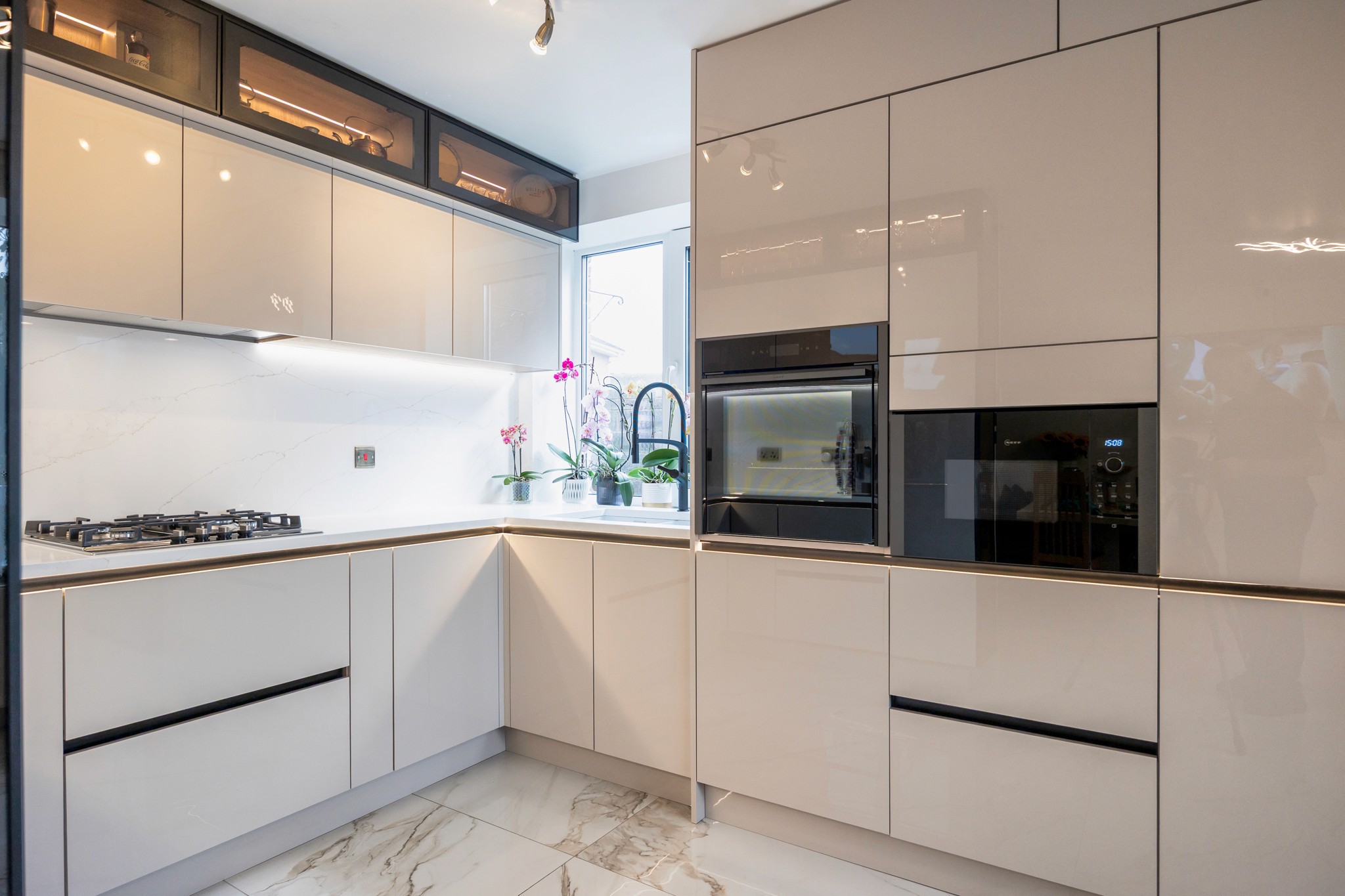 Modern two-story home with large glass windows, warmly lit interiors, and a balcony. Surrounded by trees and a manicured lawn at dusk. Cozy ambiance.