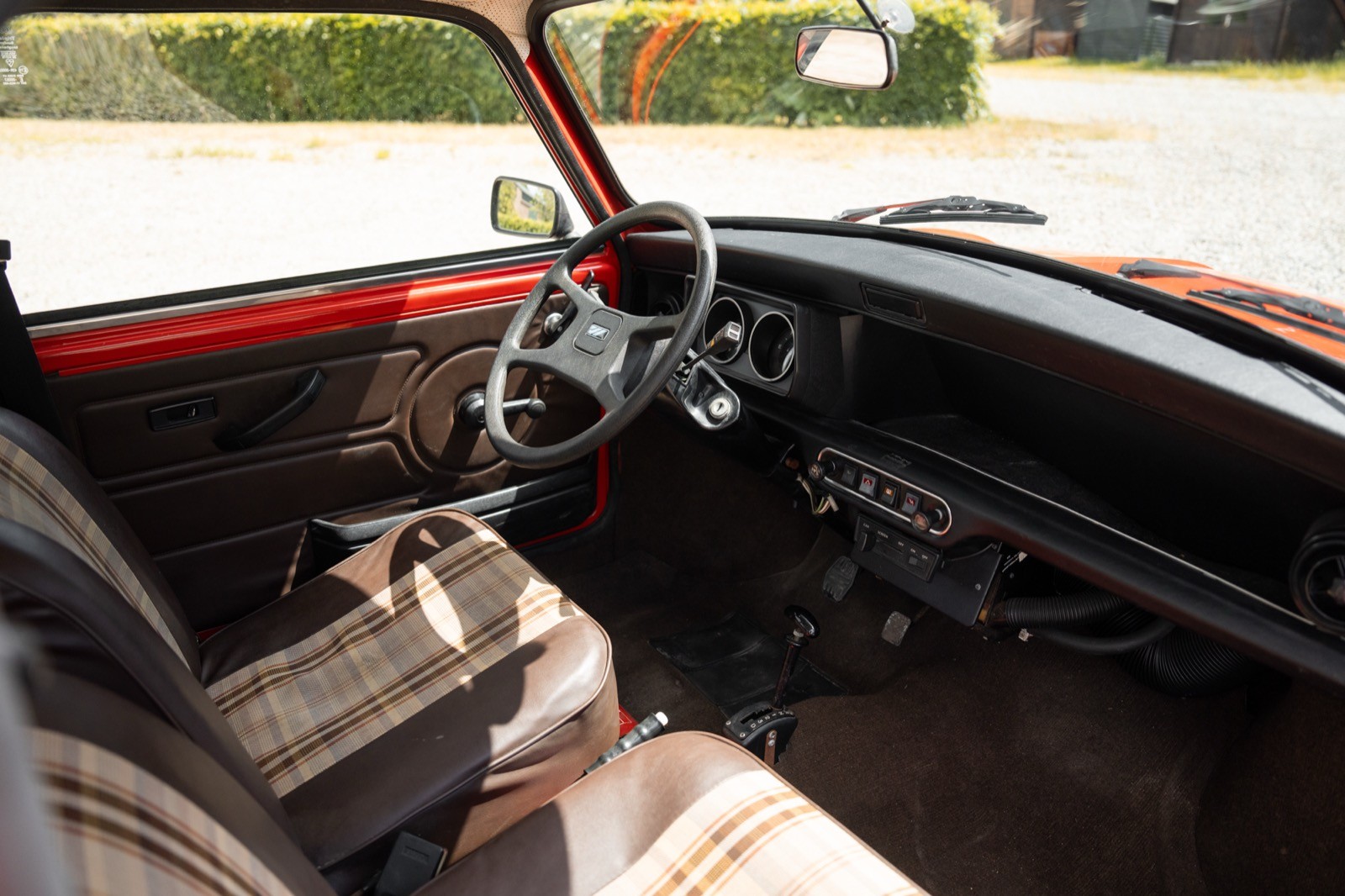 Interior of a vintage car featuring a steering wheel, seats, and dashboard with a classic design.