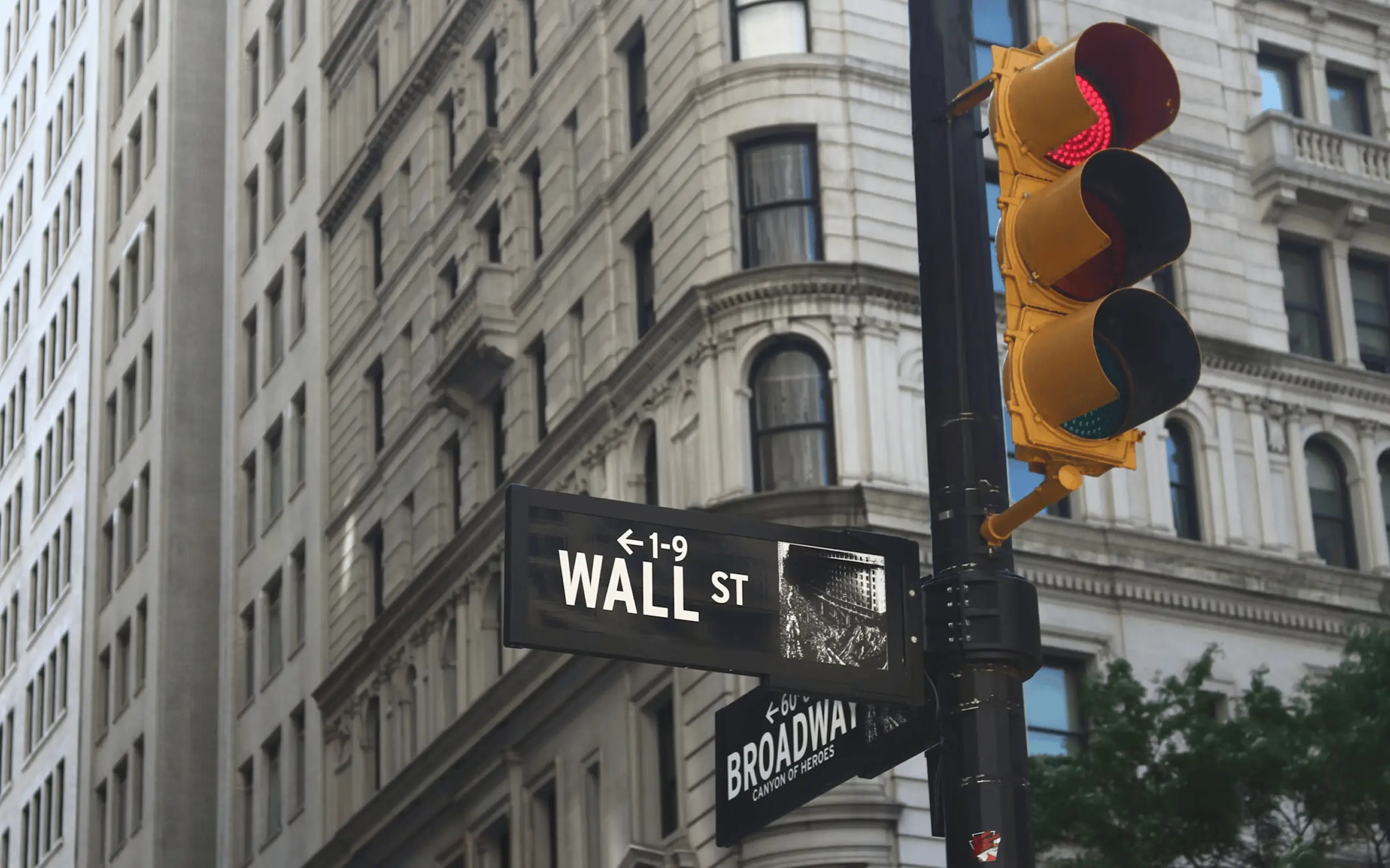 Street signs for Wall Street and Broadway on a stone building.