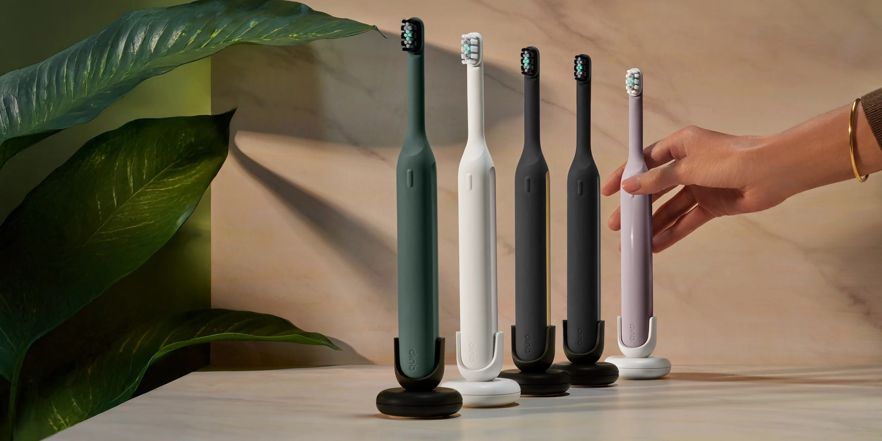 The quip Ultra color lineup, with a hand reaching for the pink brush.