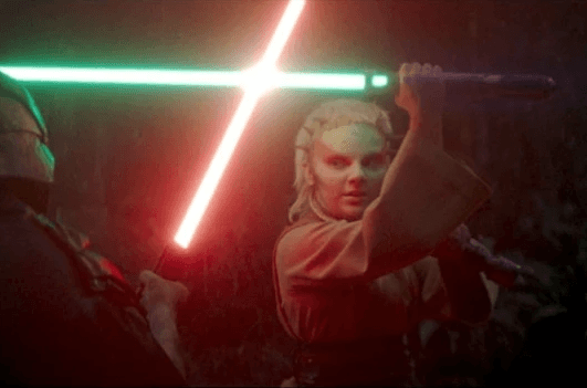 Jecki Lon holding a green lightsaber and blocking a red lightsaber