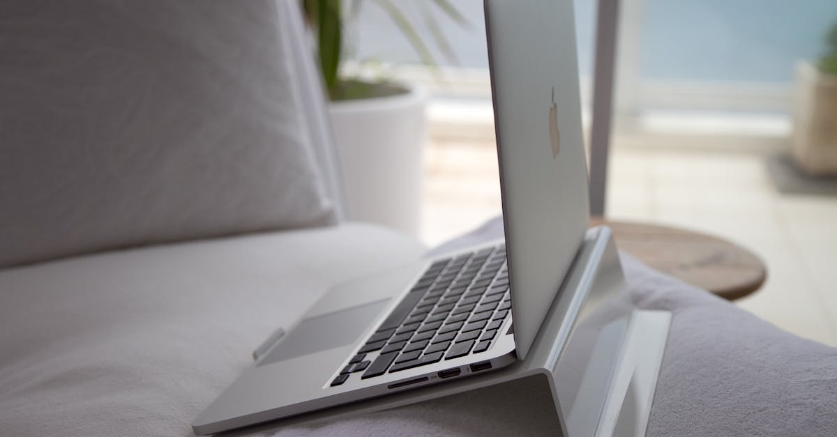 A modern laptop sits open on a cozy couch with natural sunlight streaming in.